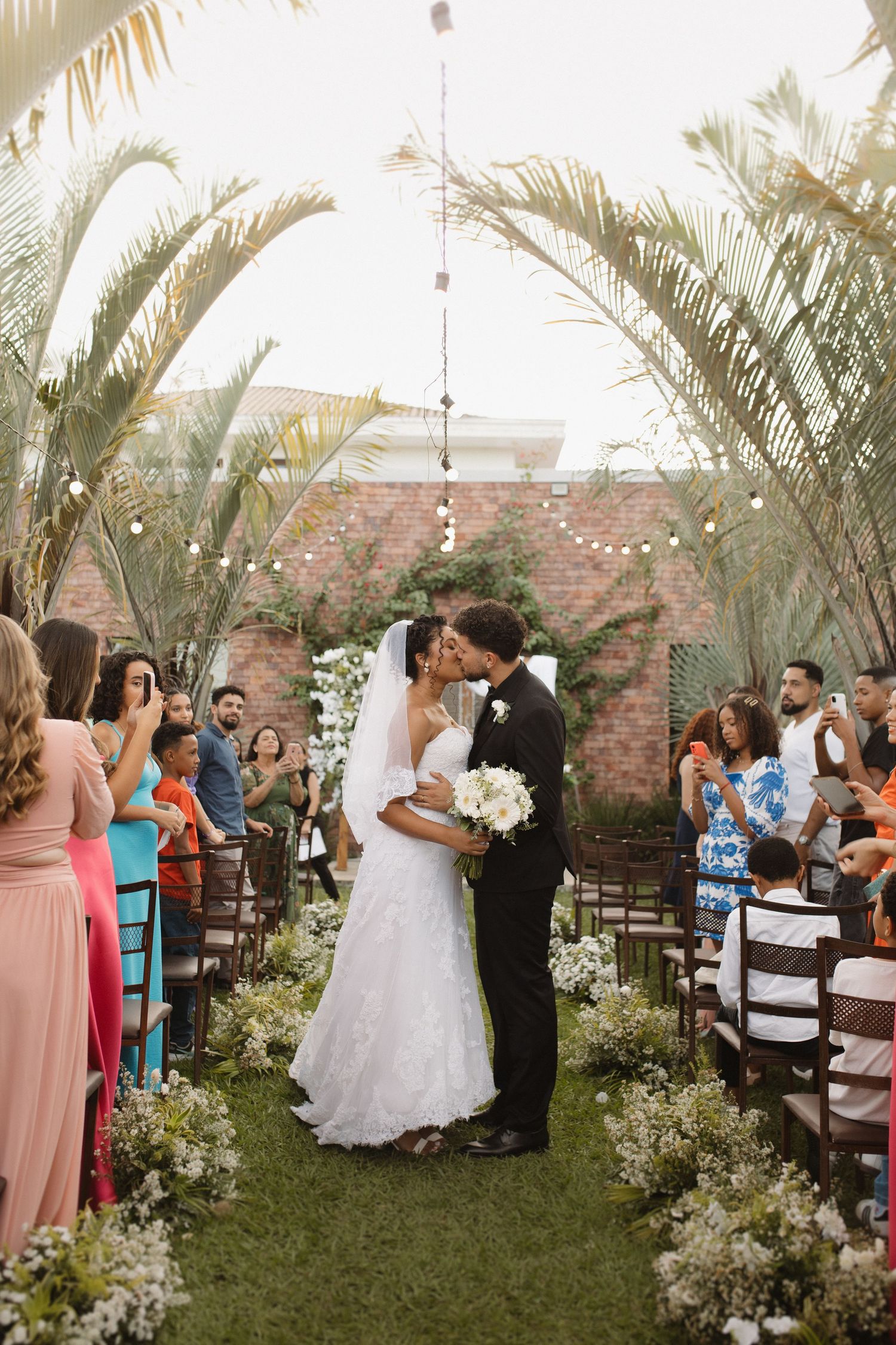 Wedding celebration in a garden courtyard with guests in colorful attire.