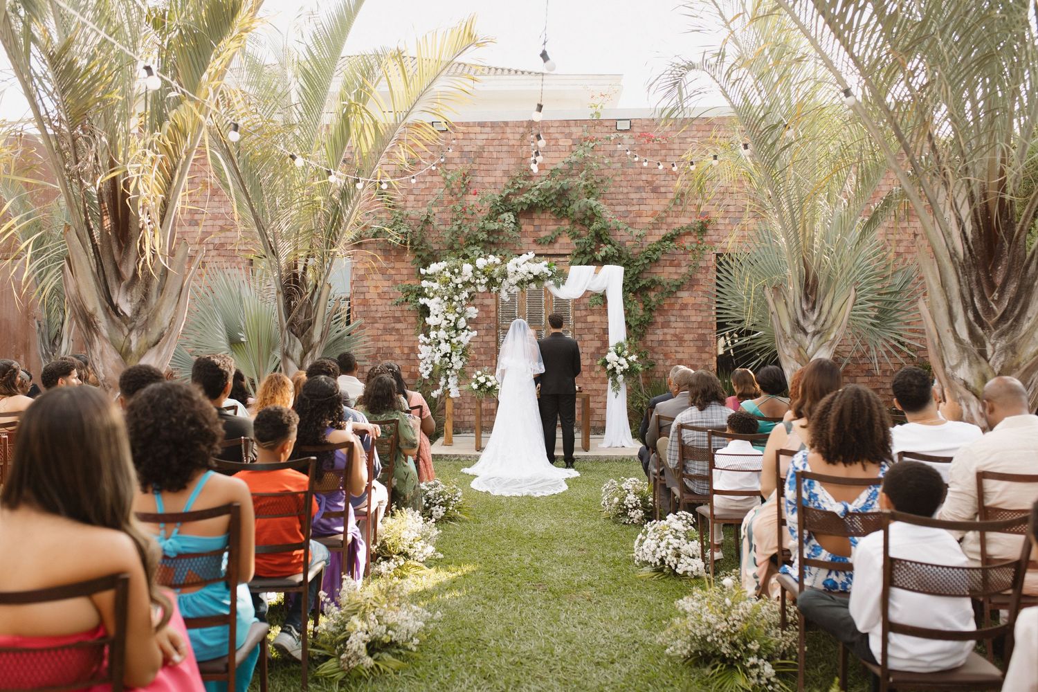Outdoor wedding ceremony setup with palm trees and rows of white chairs for guests.