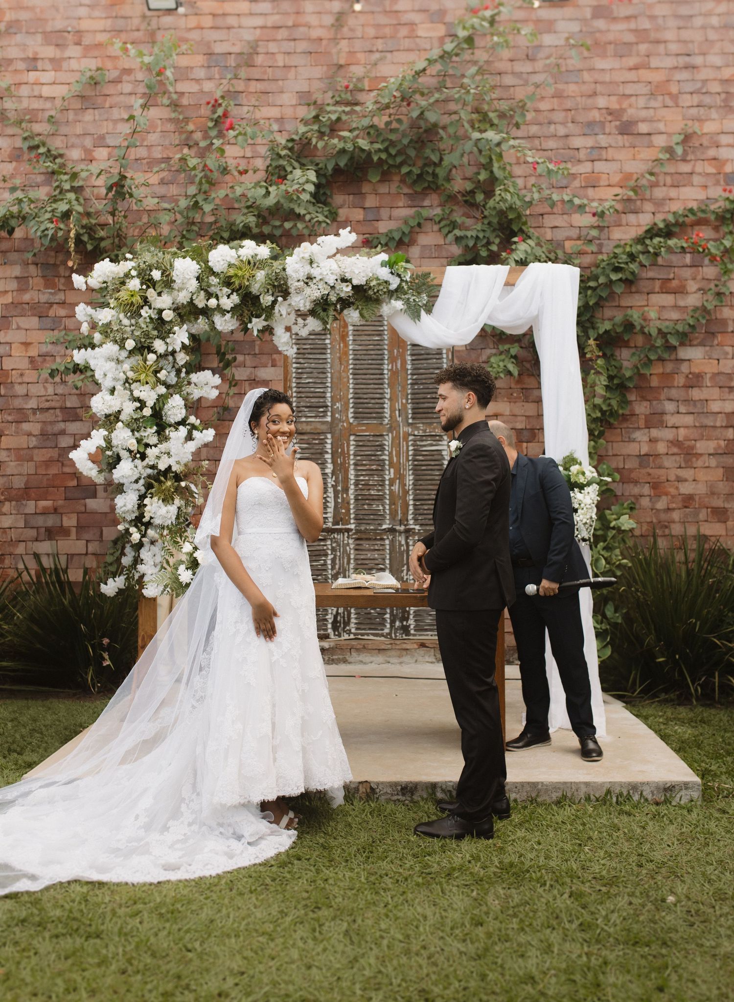 An outdoor wedding ceremony with white floral decorations and a flowing bridal gown.