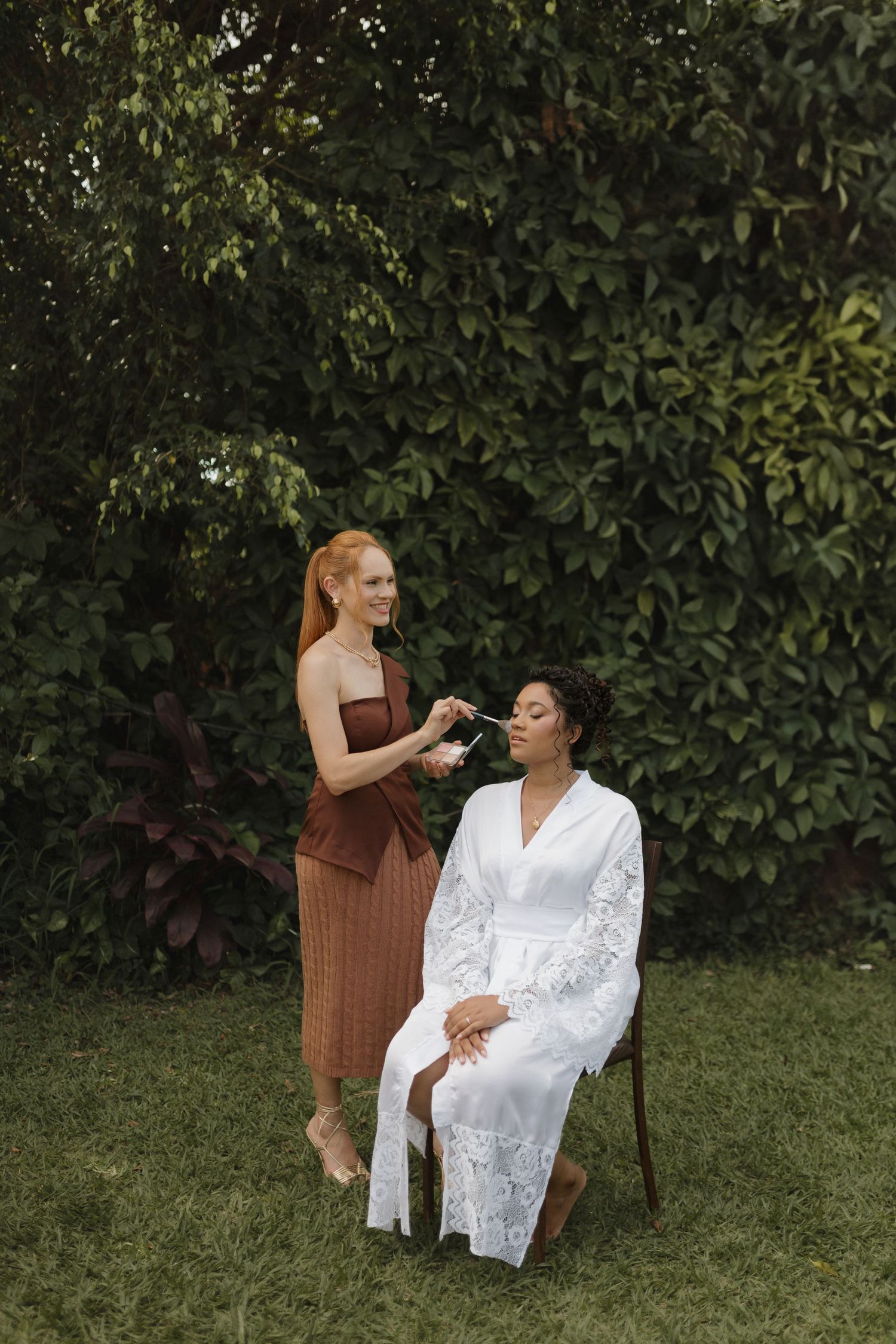 Wedding day preparation scene with makeup being applied in an outdoor garden setting.