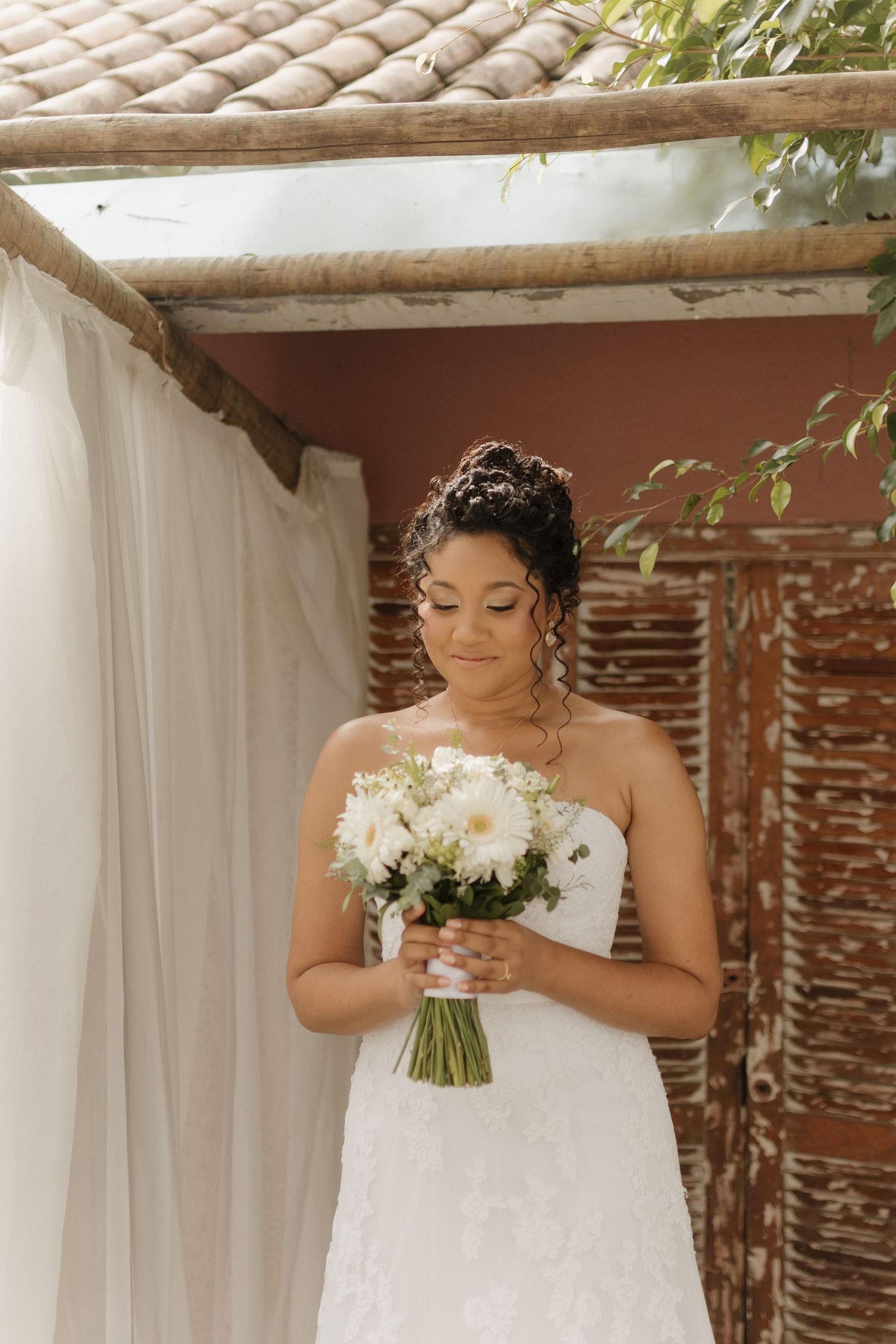 Elegant bridal portraits under a covered patio with white drapes and terra cotta roof.