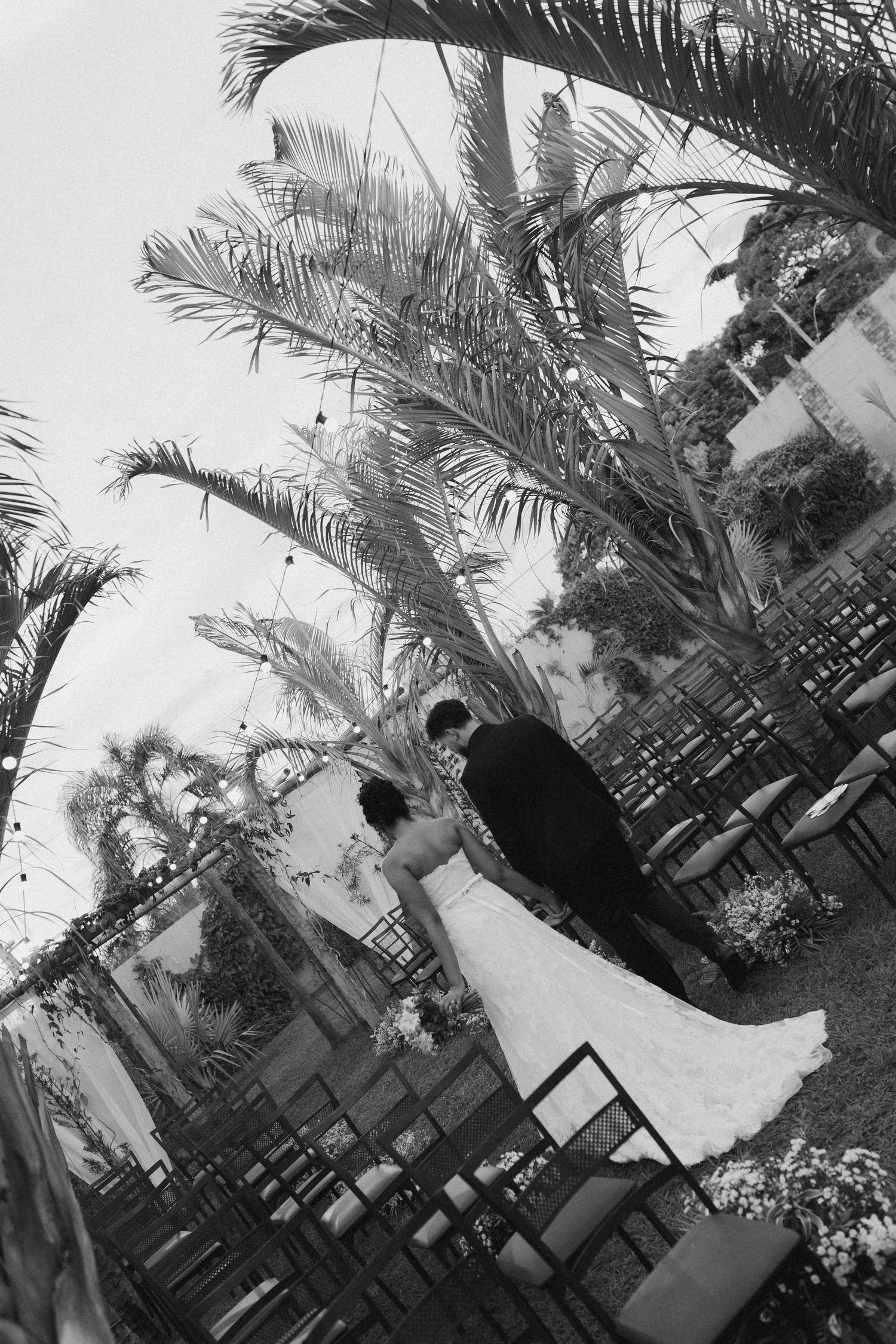 Black and white wedding reception scene with palm trees and outdoor decor.