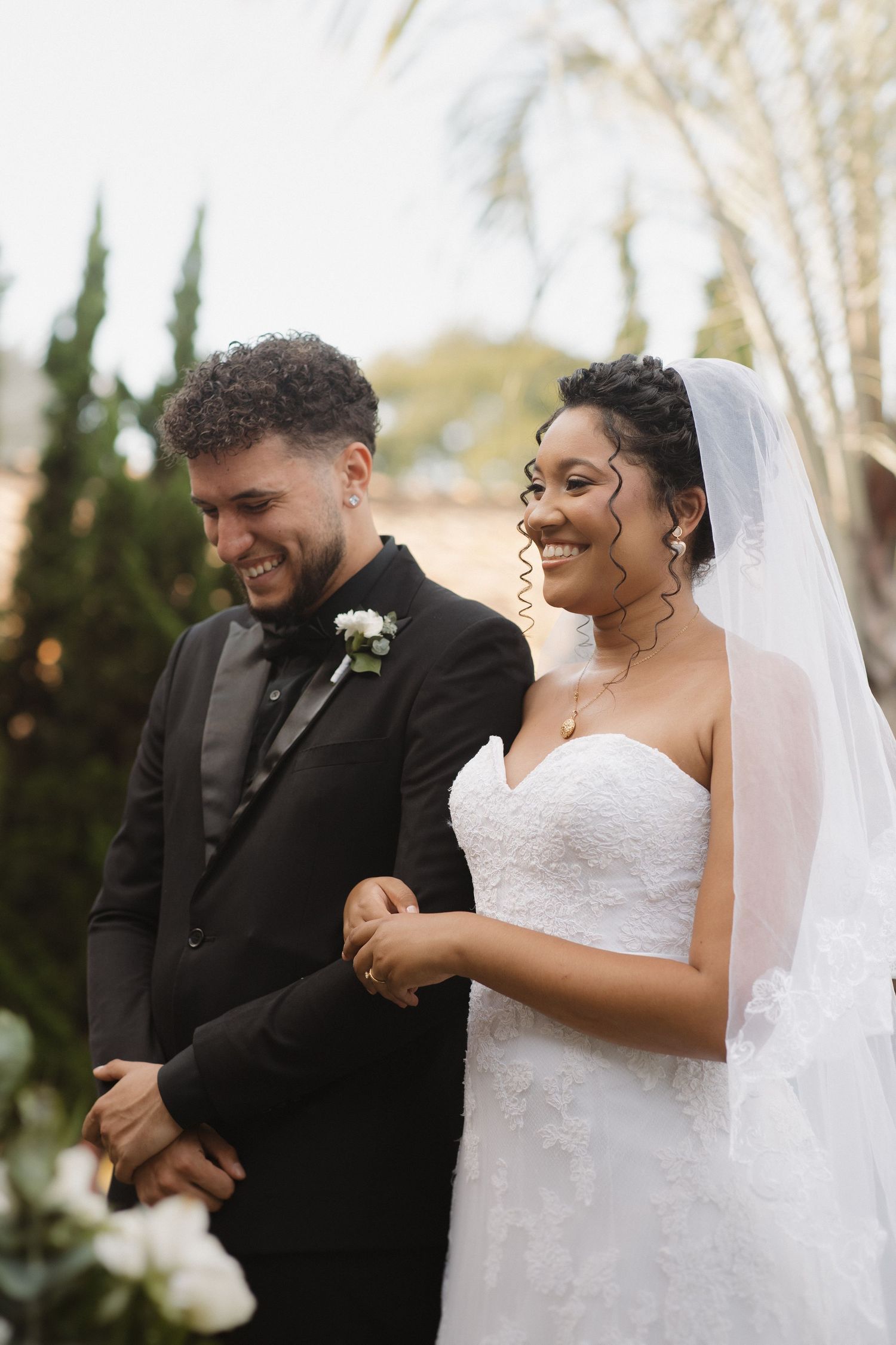 Candid moments of laughter shared during a wedding ceremony under palm trees.