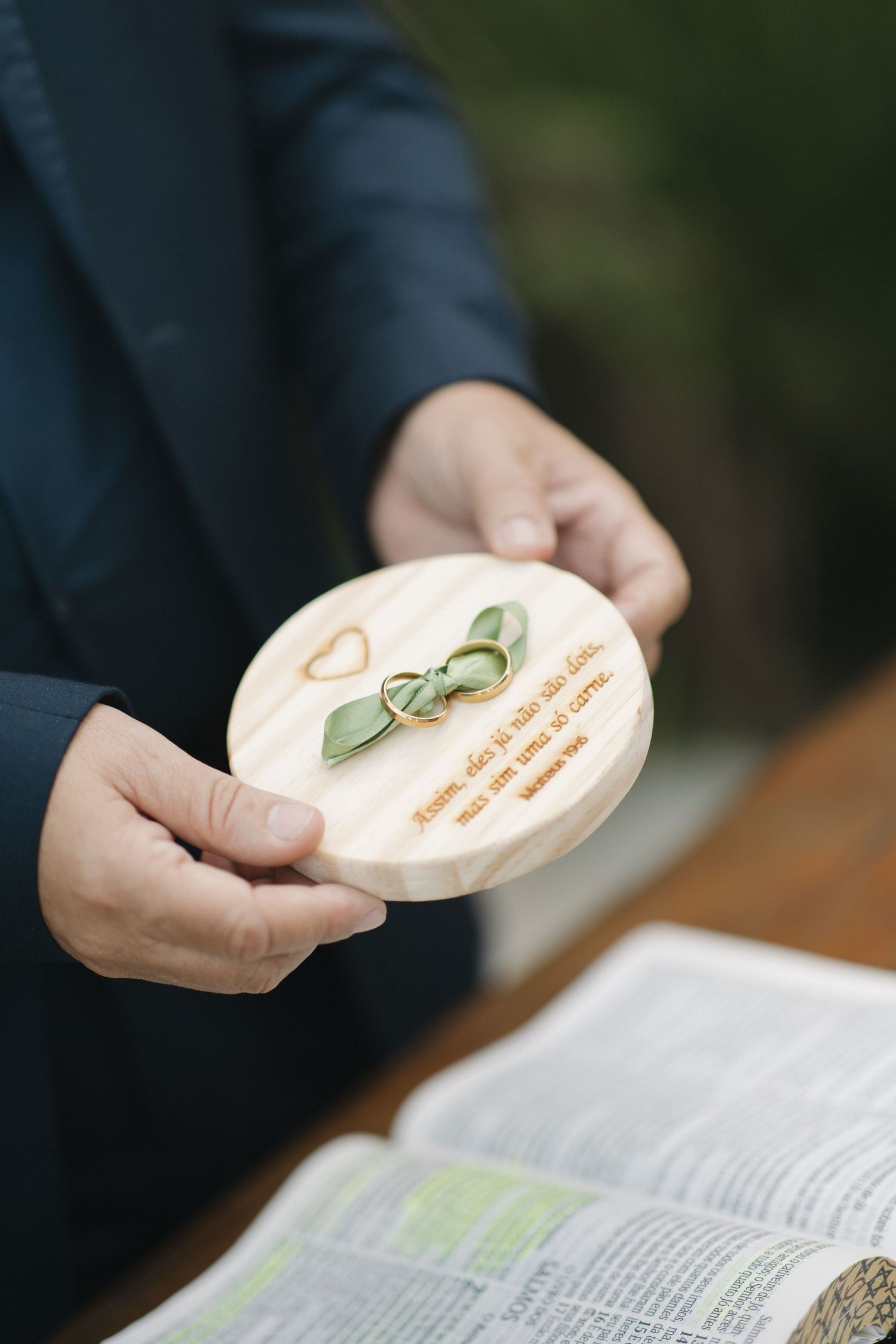 Close-up of hands holding a wooden ring box over an open book.