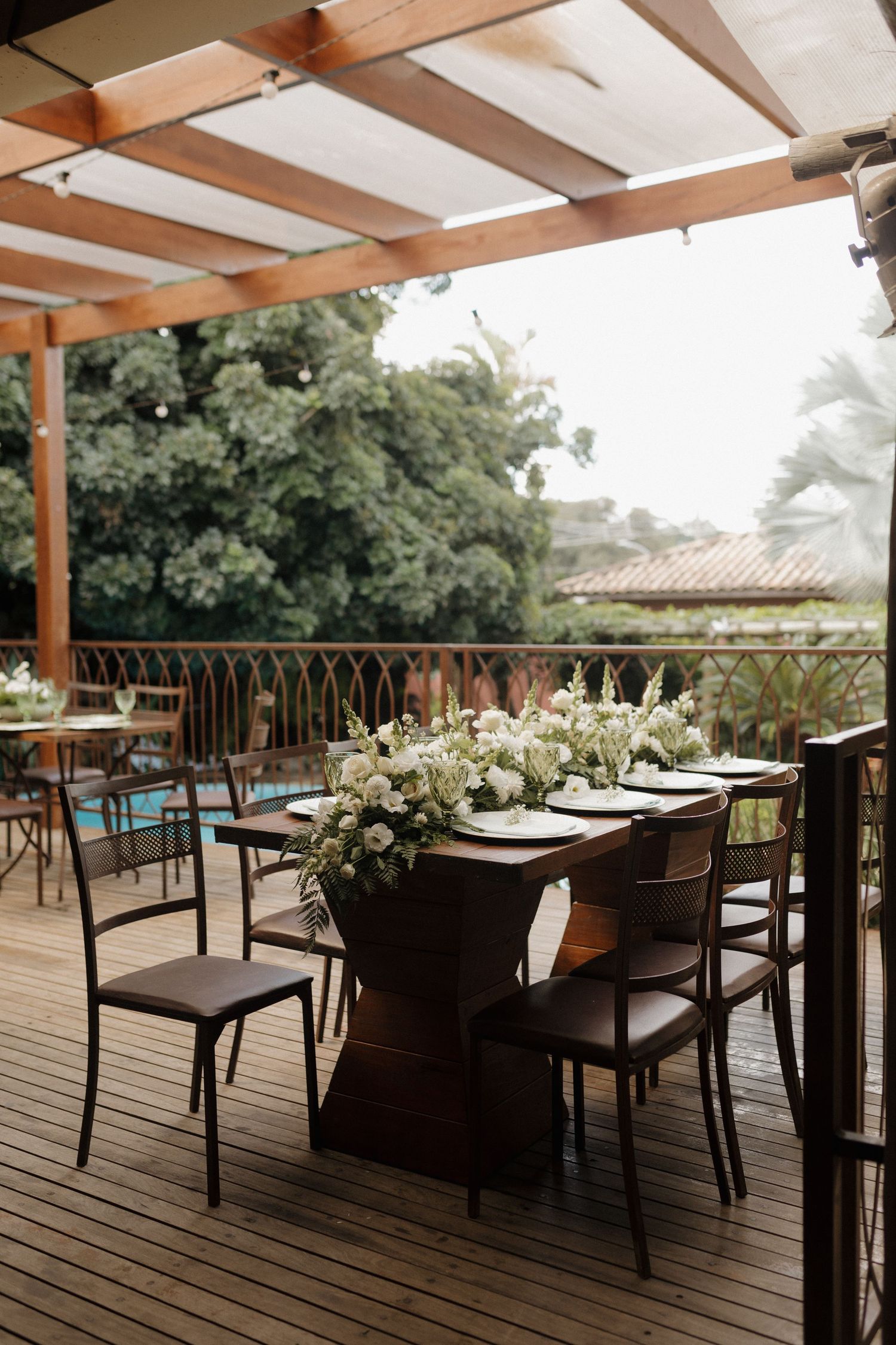 Outdoor dining area with wooden pergola and tables set for an elegant event.