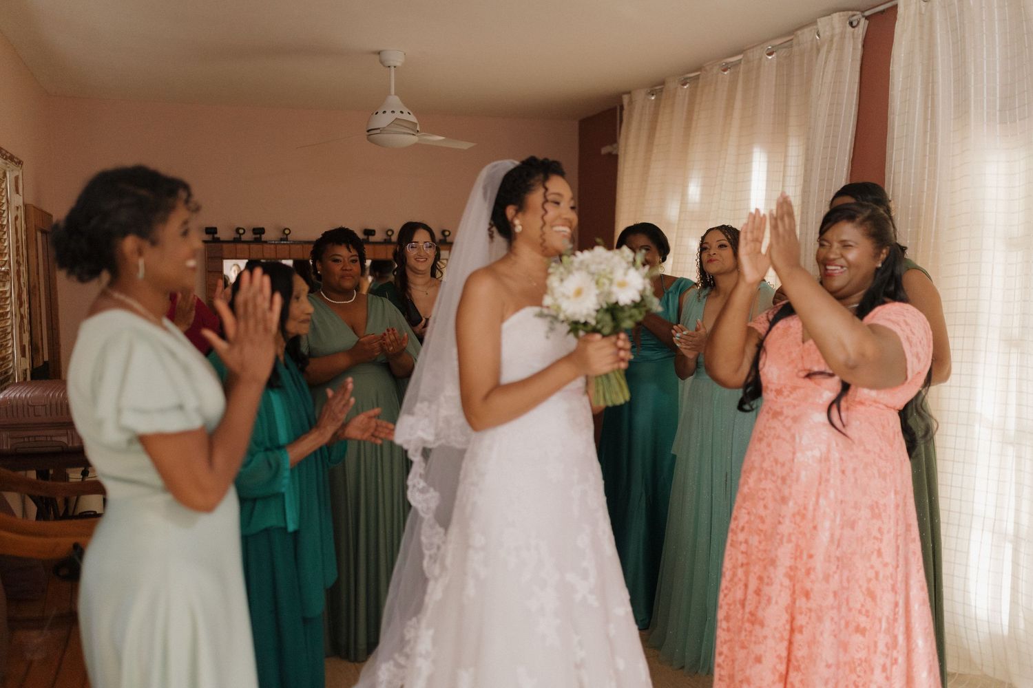 Wedding celebration indoors with bridesmaids in teal dresses and guests in formal attire.