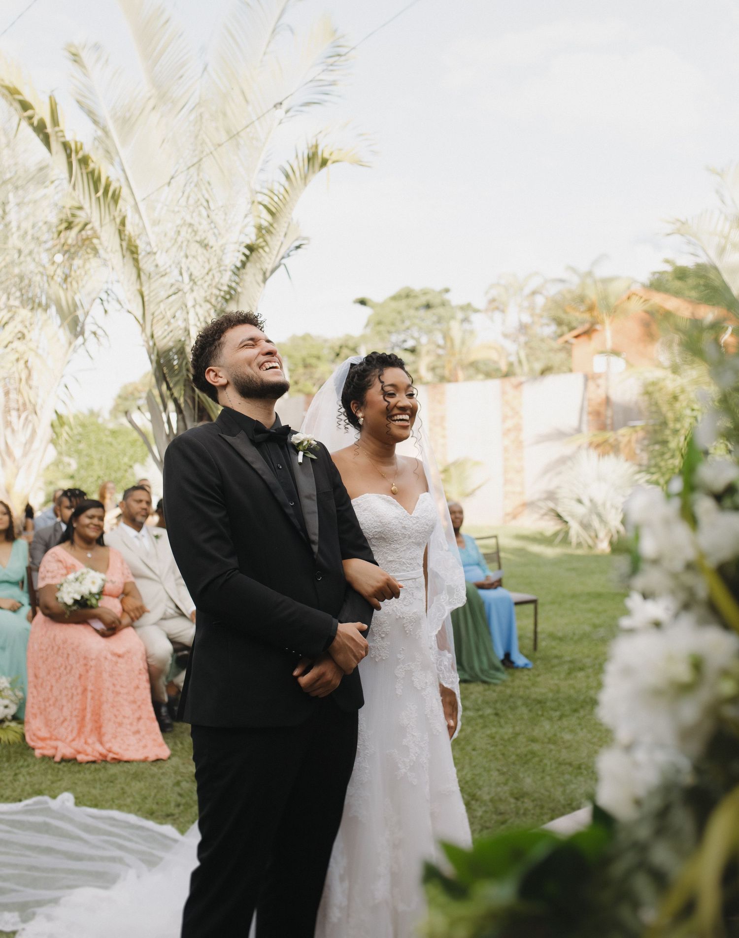 Joyful moments captured during an outdoor wedding ceremony with palm trees in the background.