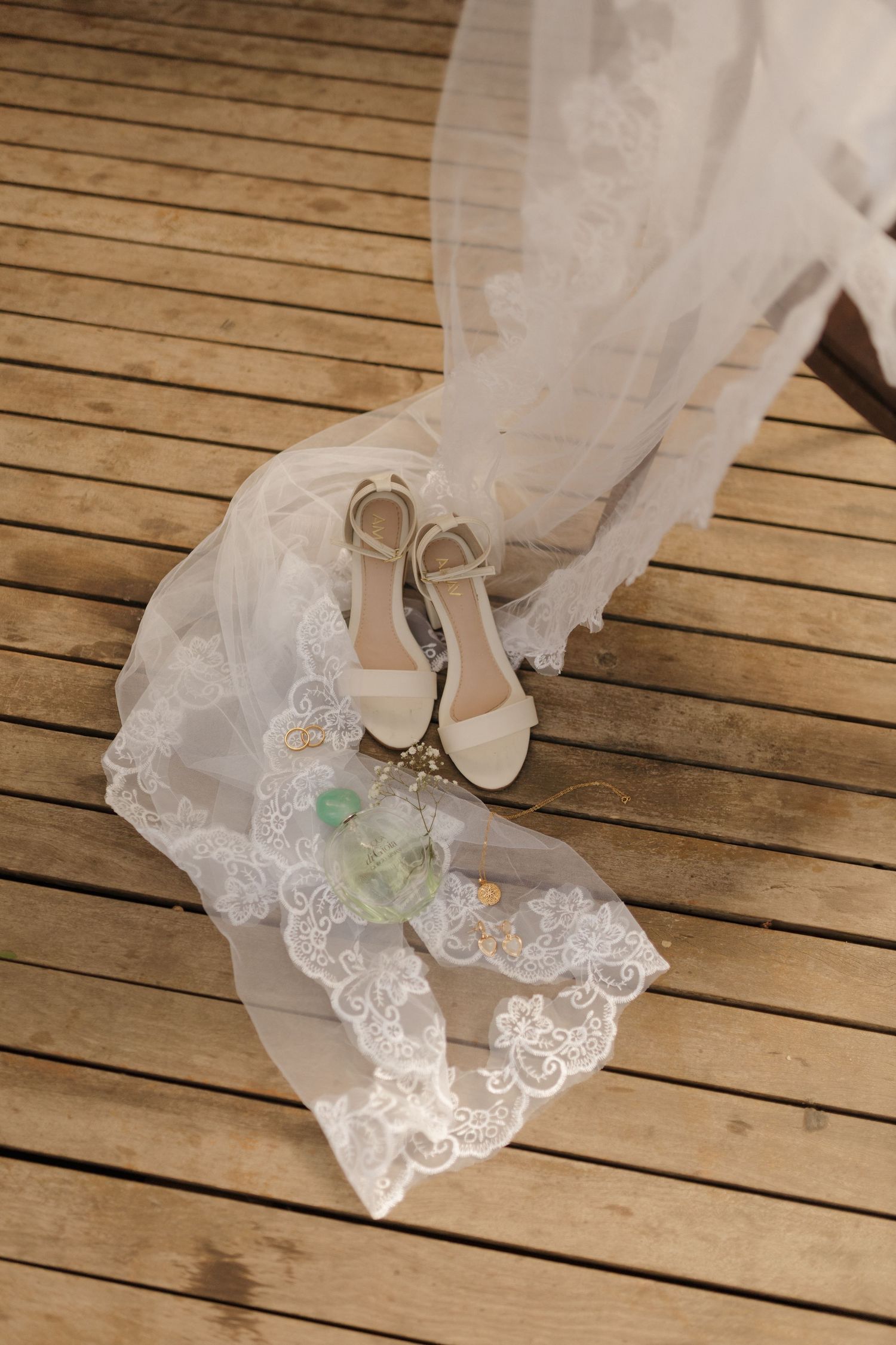 Delicate lace detail of a wedding dress train displayed on wooden deck flooring.