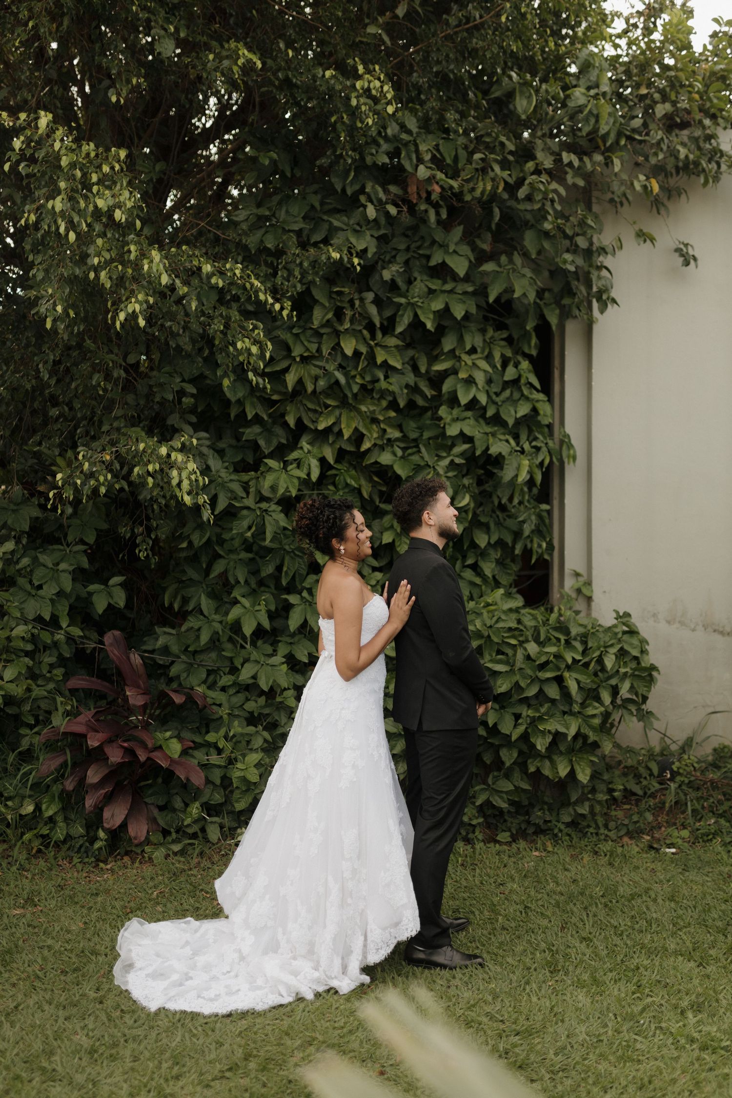 A couple in wedding attire shares an intimate moment in a lush garden setting.