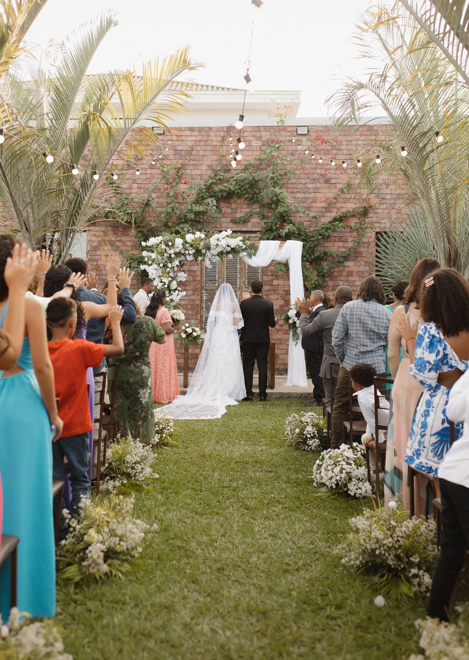 Outdoor wedding venue with brick wall backdrop and tropical palm trees.