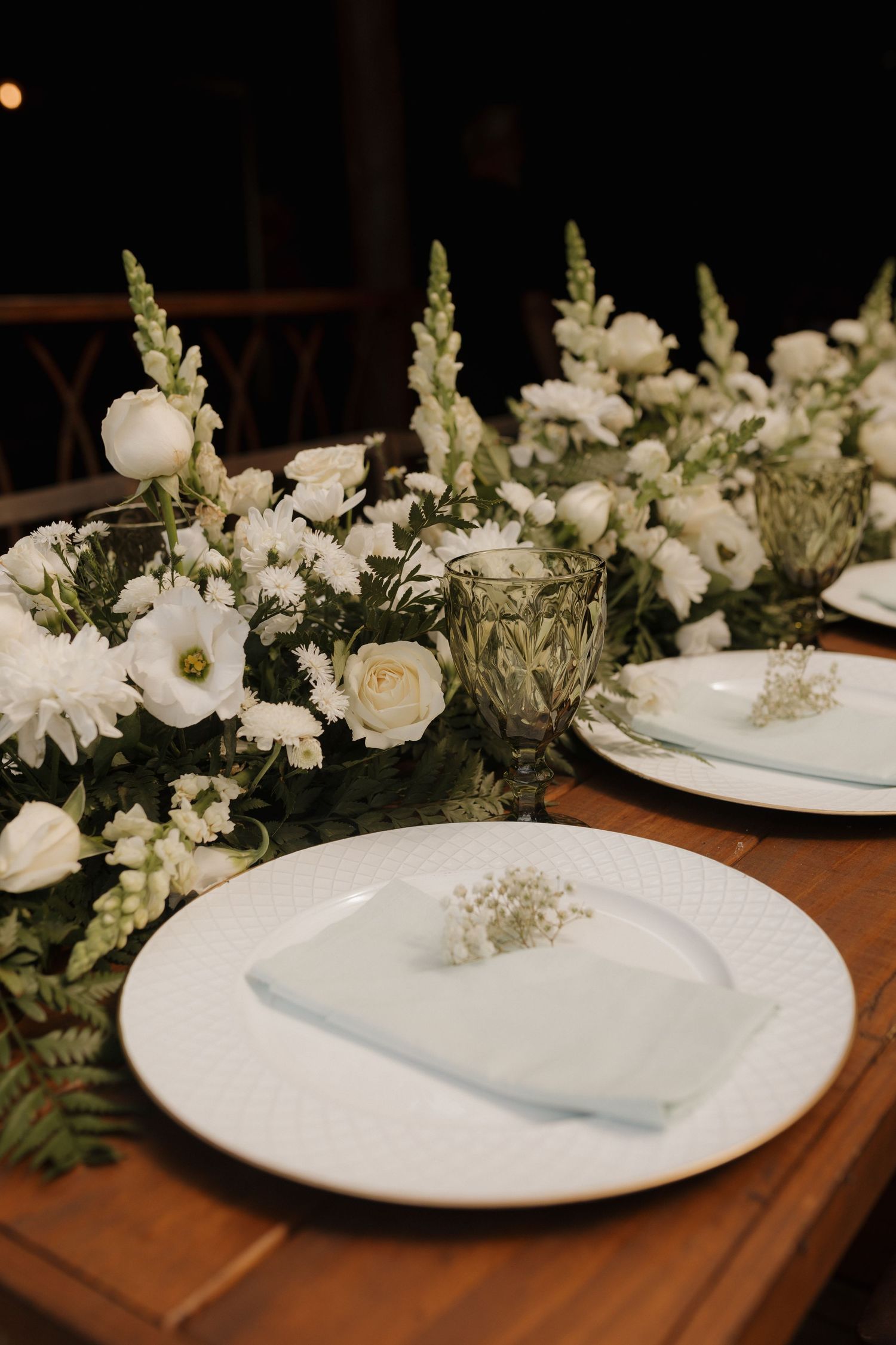 Elegant table settings with white floral centerpieces and delicate place settings on wooden tables.