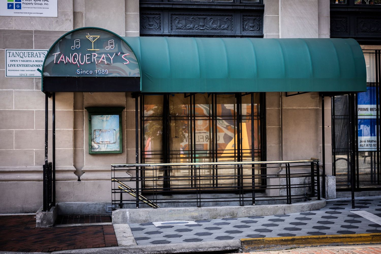 Tanqueray's bar and restaurant exterior with green awning on a city street corner.