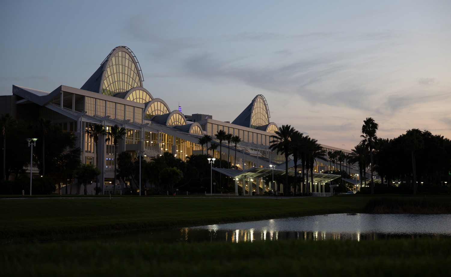 Orange County Convention Center illuminated at dusk reflecting in a nearby pond in Orlando Florida.