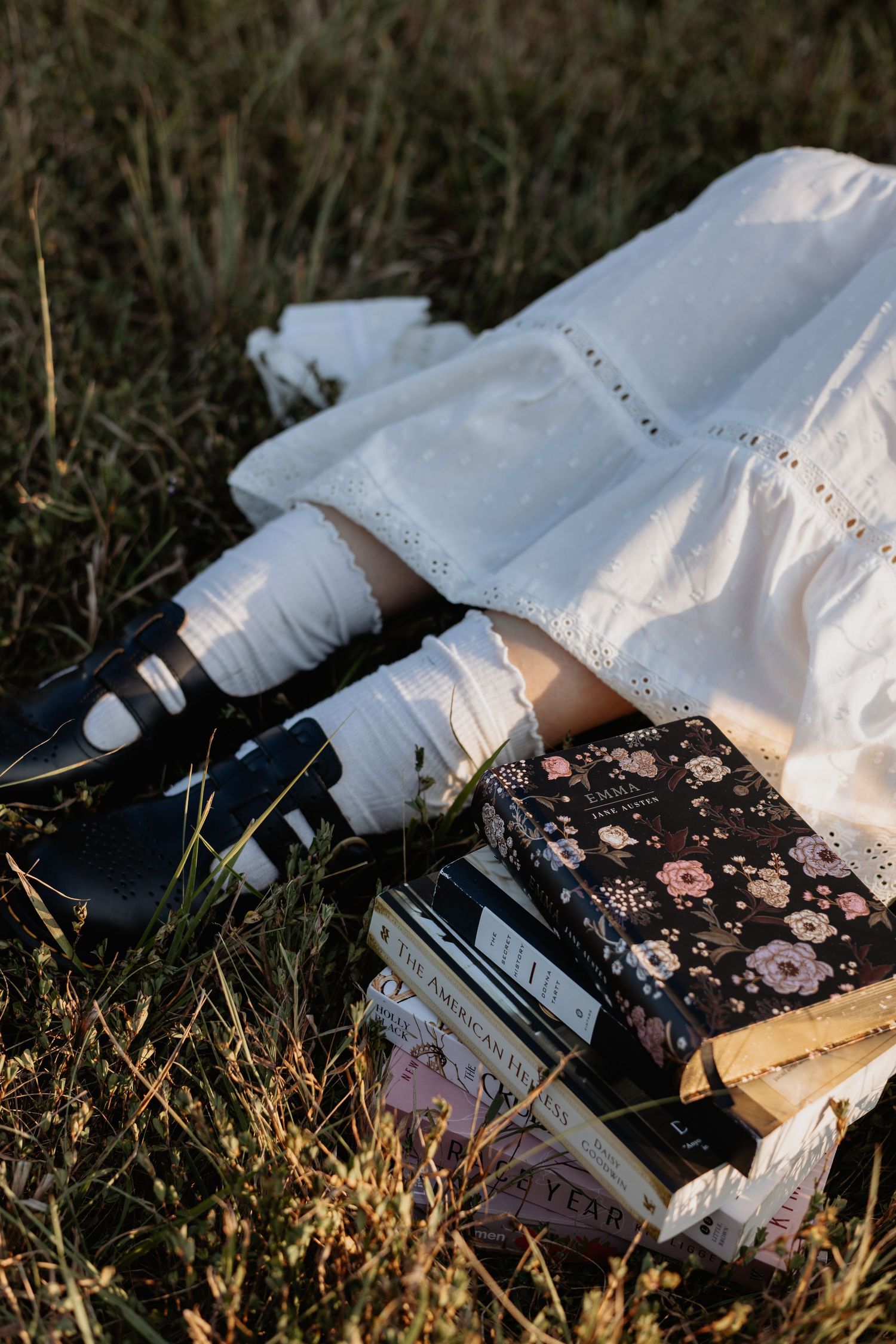 Close-up of white dress and books arranged on grass with floral book covers.