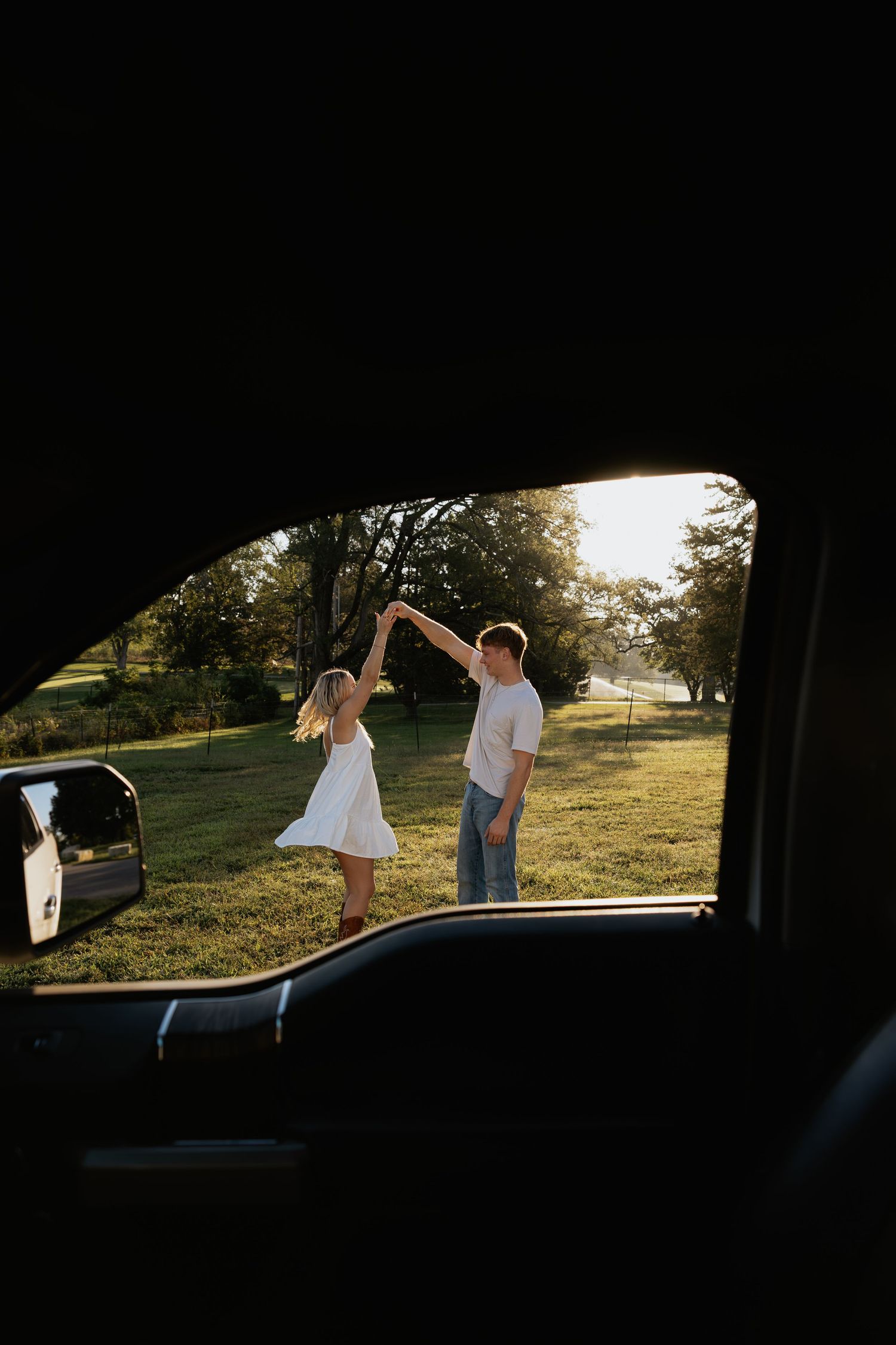 Silhouettes of a couple viewed through a car window at sunset.