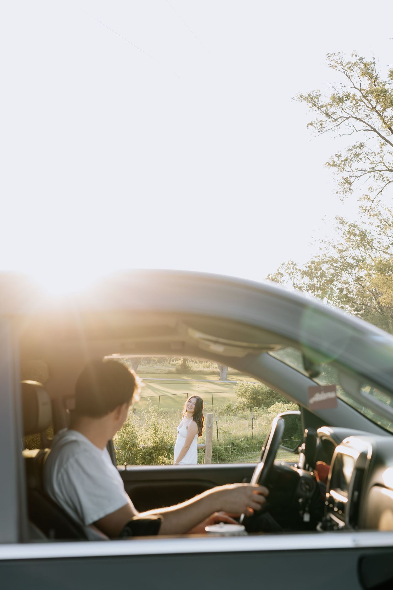 A sunny scene through a car window with trees in the background.