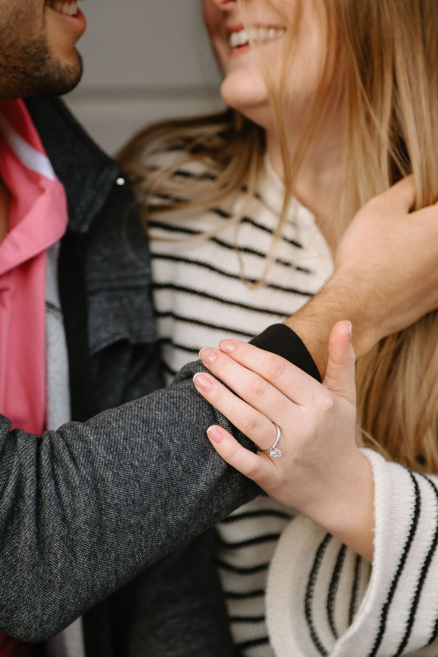 Close up of couple embracing, focusing on engagement ring.