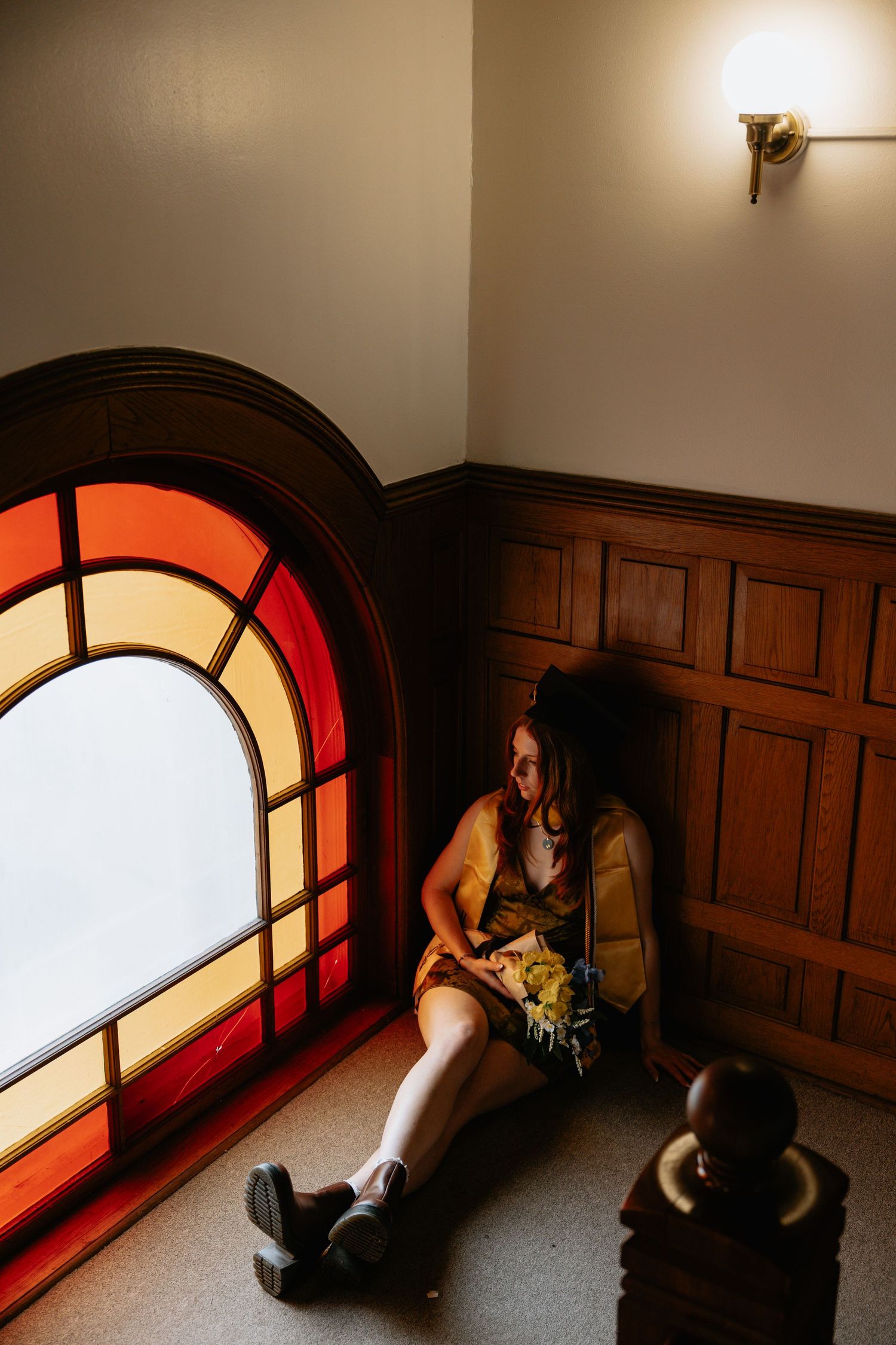 Dramatic lighting through arched windows creates shadows in wood-paneled hallway.