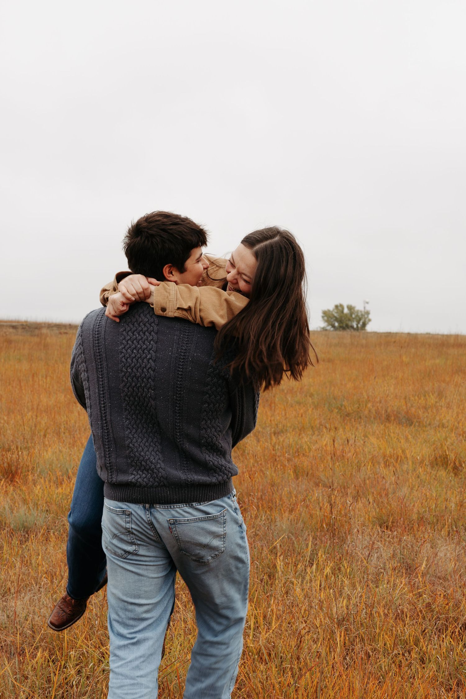 A couple playfully spinning in a golden autumn field.