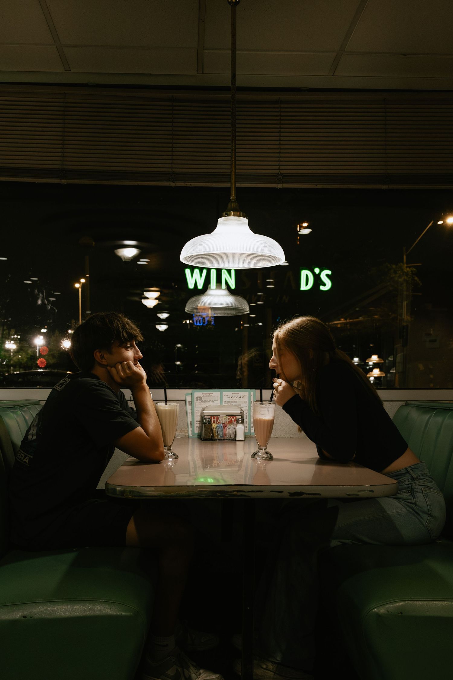 Dimly lit diner scene with vintage pendant lamps and booth seating.