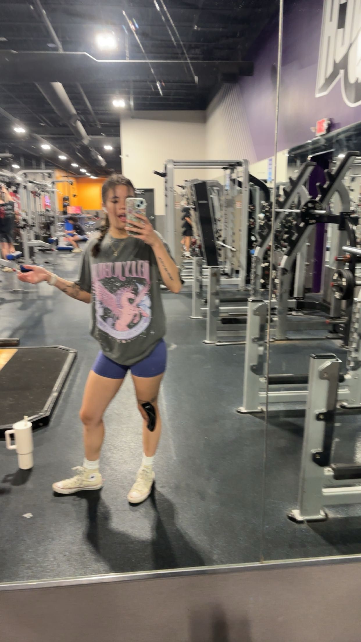 Person posing in mirrors at modern gym.