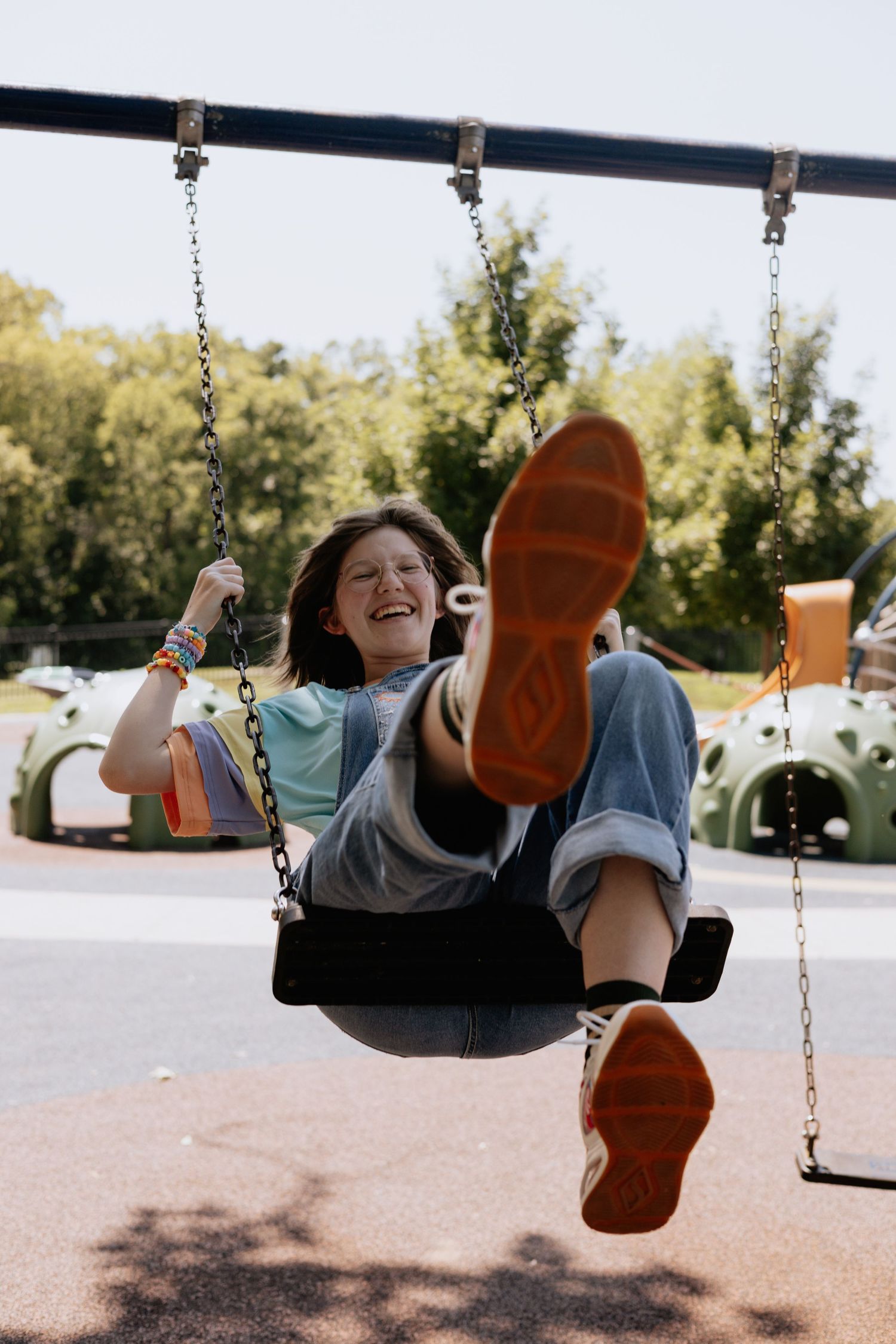 Person swinging joyfully at a playground on a sunny day, captured in a sequence of action shots.
