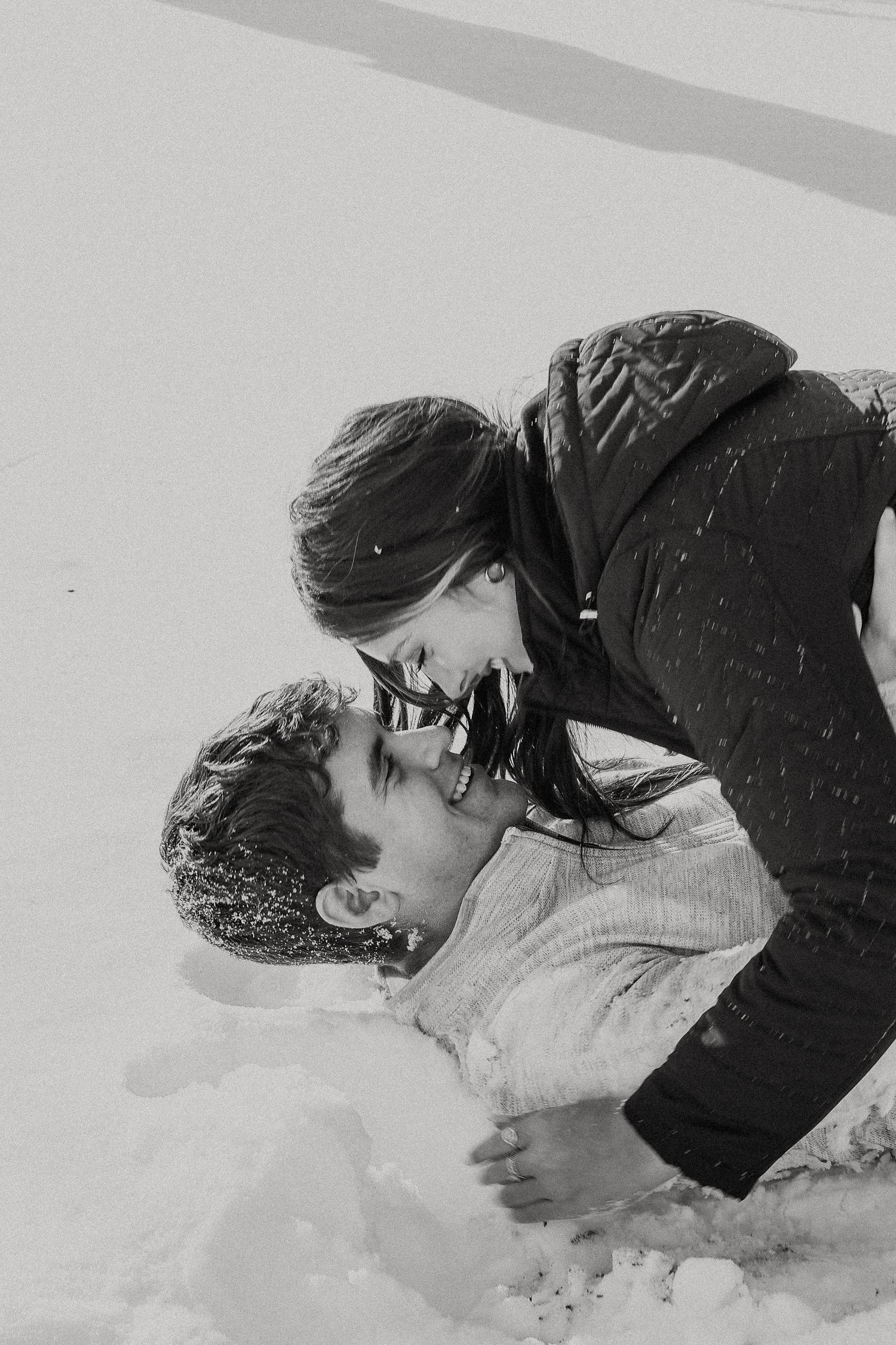 Couple lying in deep snow during winter.