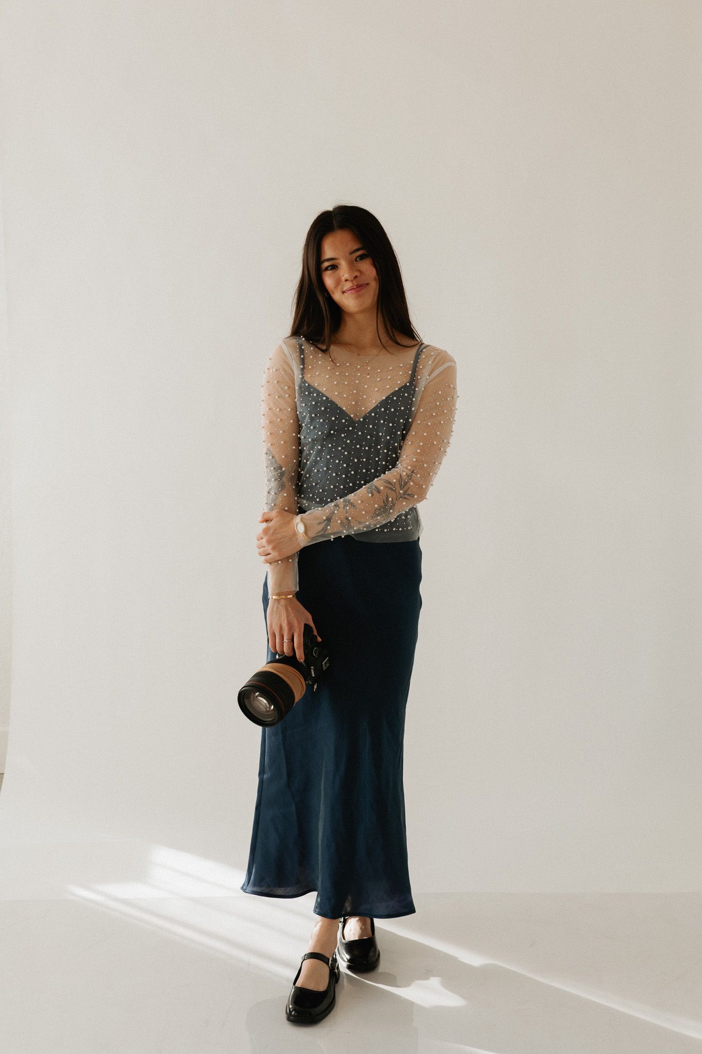 Studio fashion portrait in patterned top and navy skirt with natural lighting.