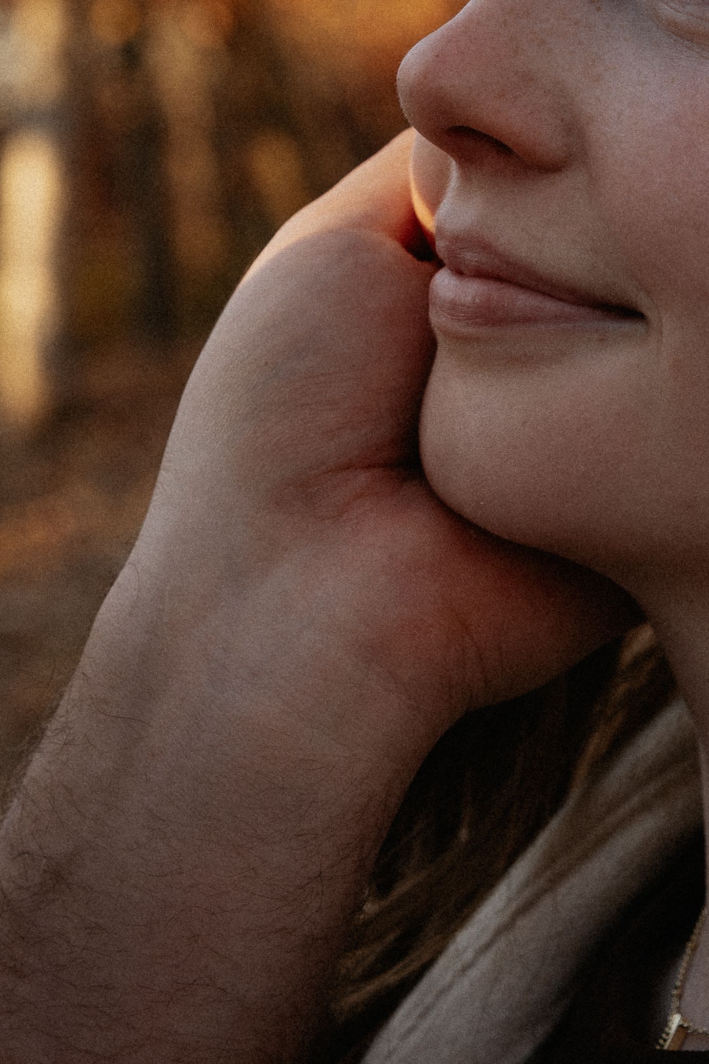 Close-up shot of hands tenderly touching in warm sunlight.