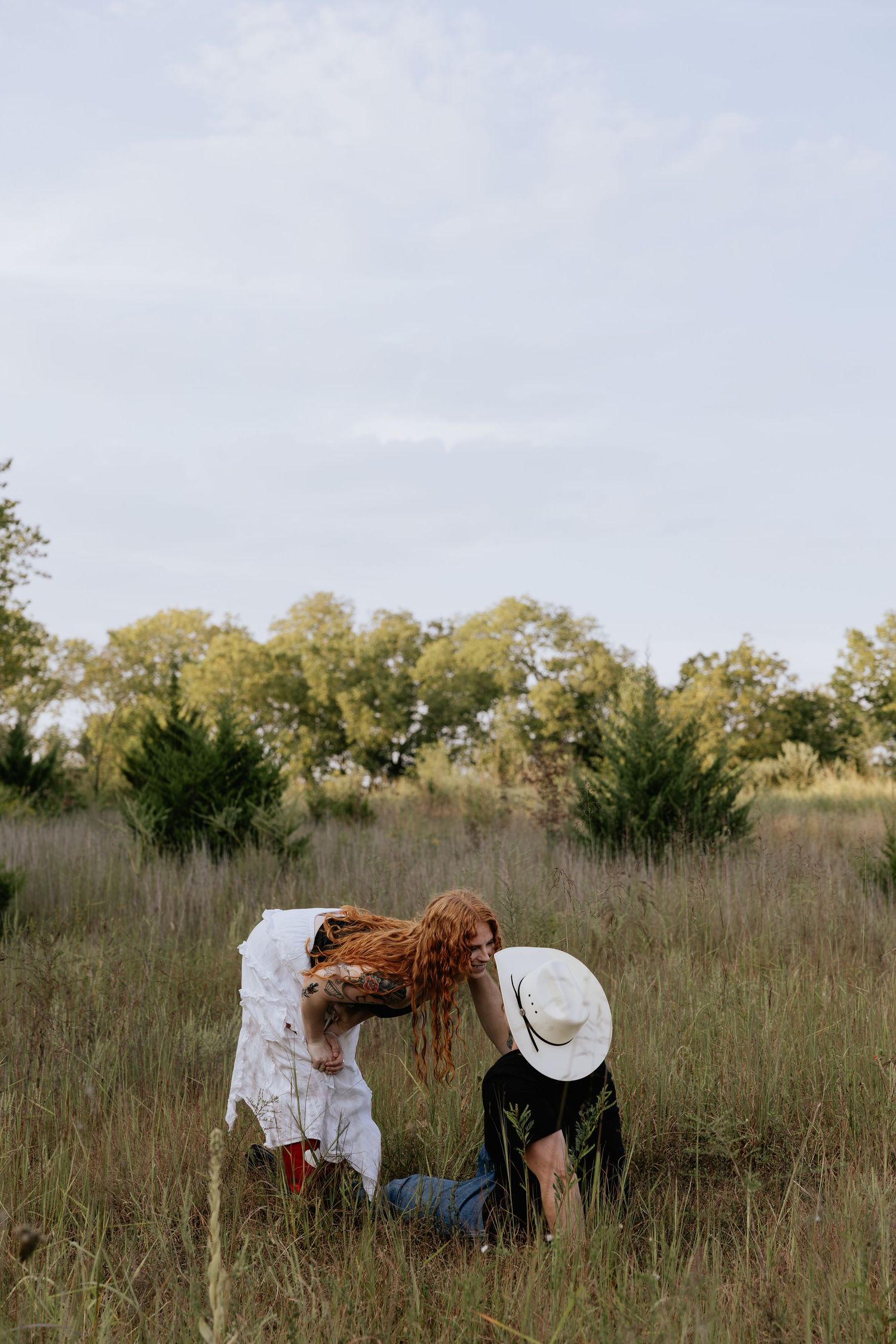 Playful interaction in a rustic field with white cowboy hat.