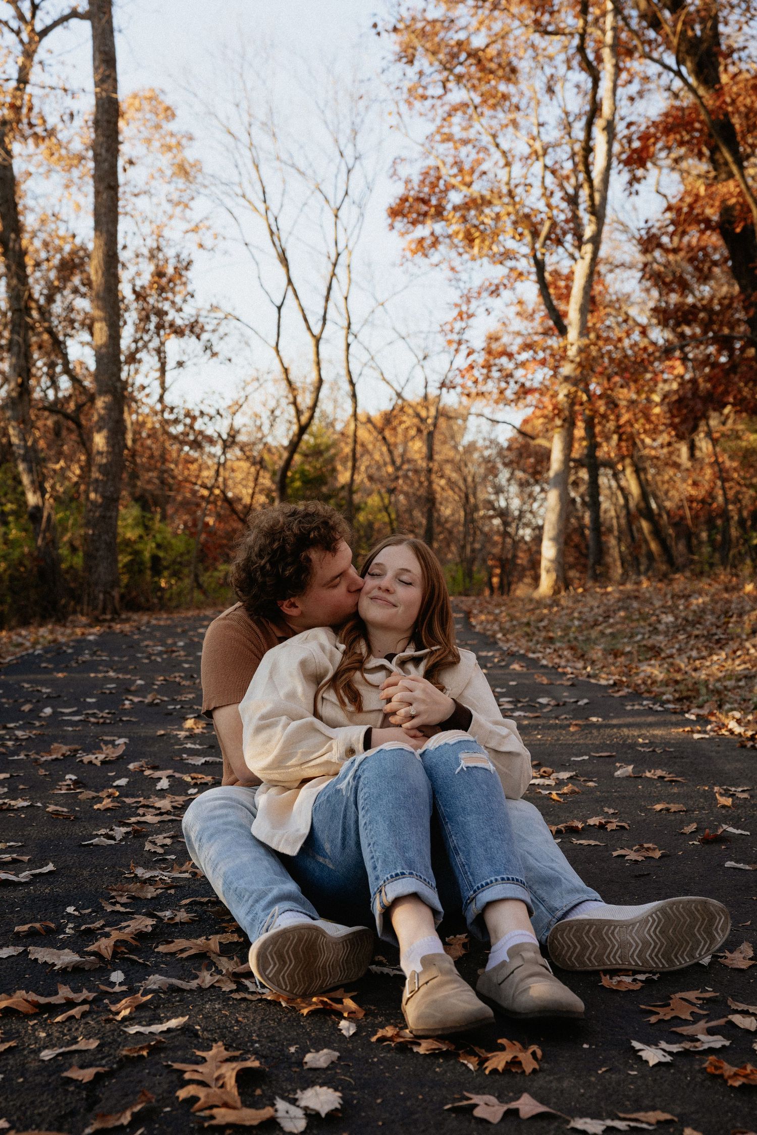 Couple lying on autumn leaves sharing intimate moments in natural outdoor setting.