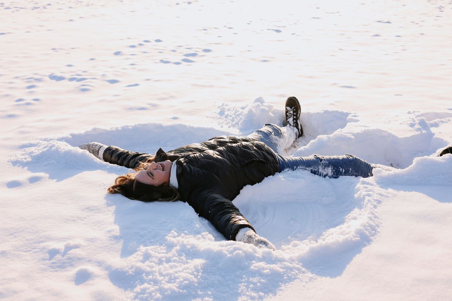 People making snow angels in fresh white snow on a winter day.