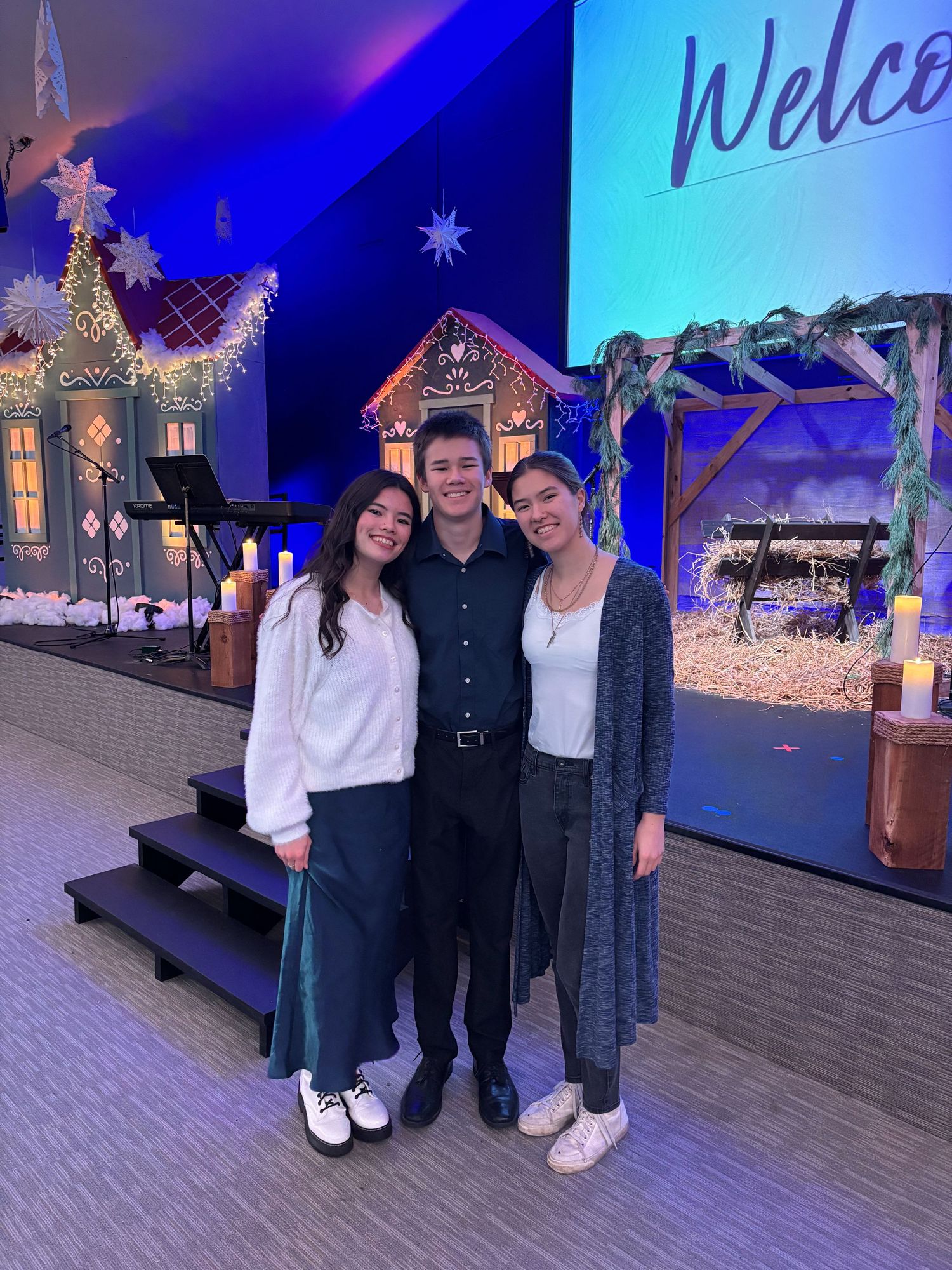 Group photo in front of blue-lit winter wonderland themed backdrop at an indoor event.