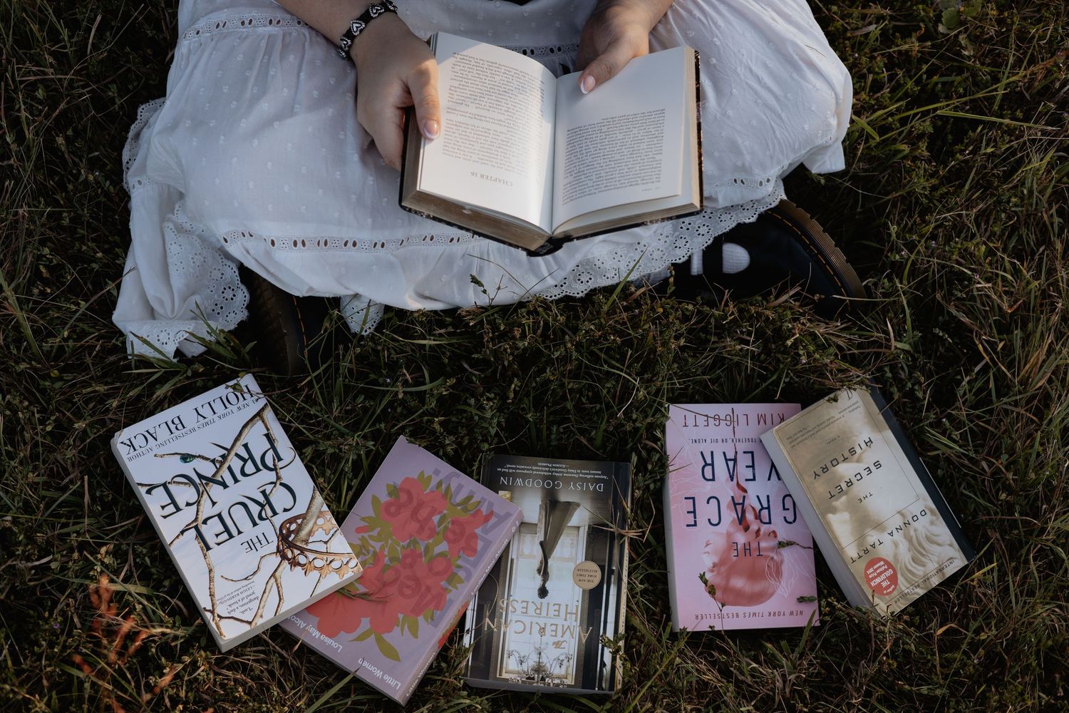Books and papers scattered on grass in what appears to be a collection of discarded reading materials.