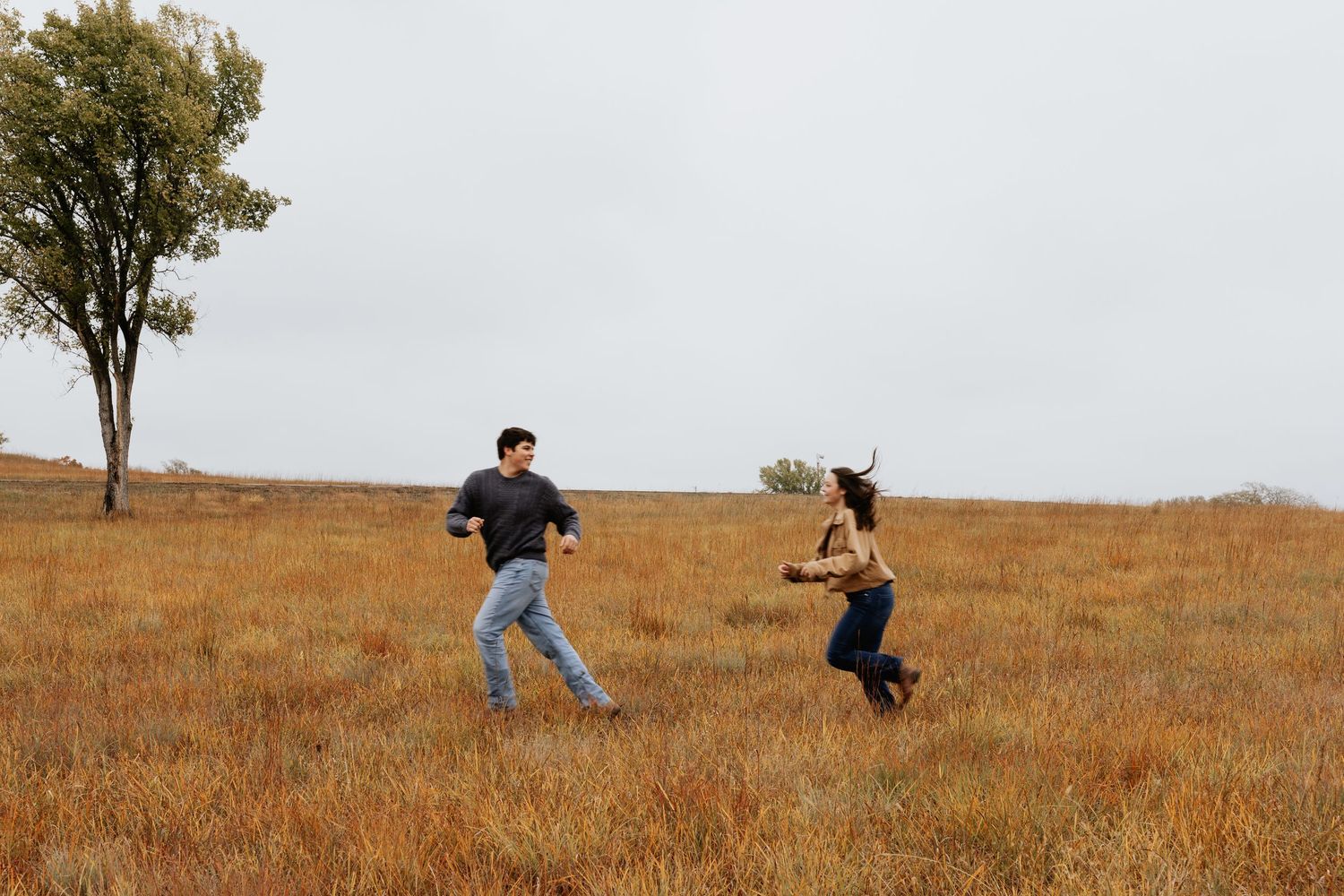 Two people running and playing in a rustic autumn field.