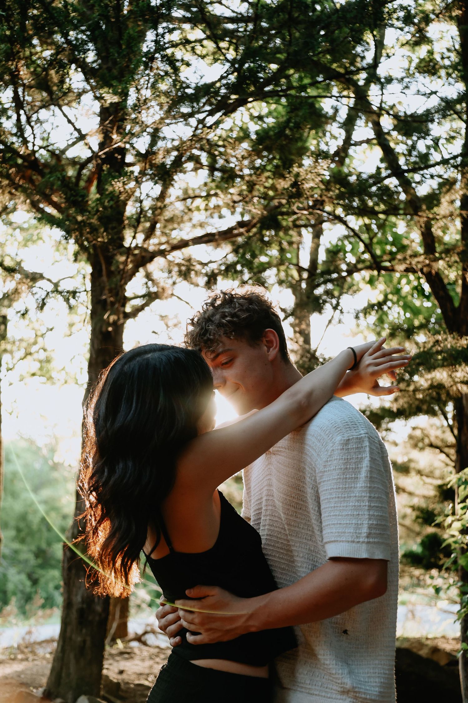 A backlit romantic moment between trees with sunlight streaming through.