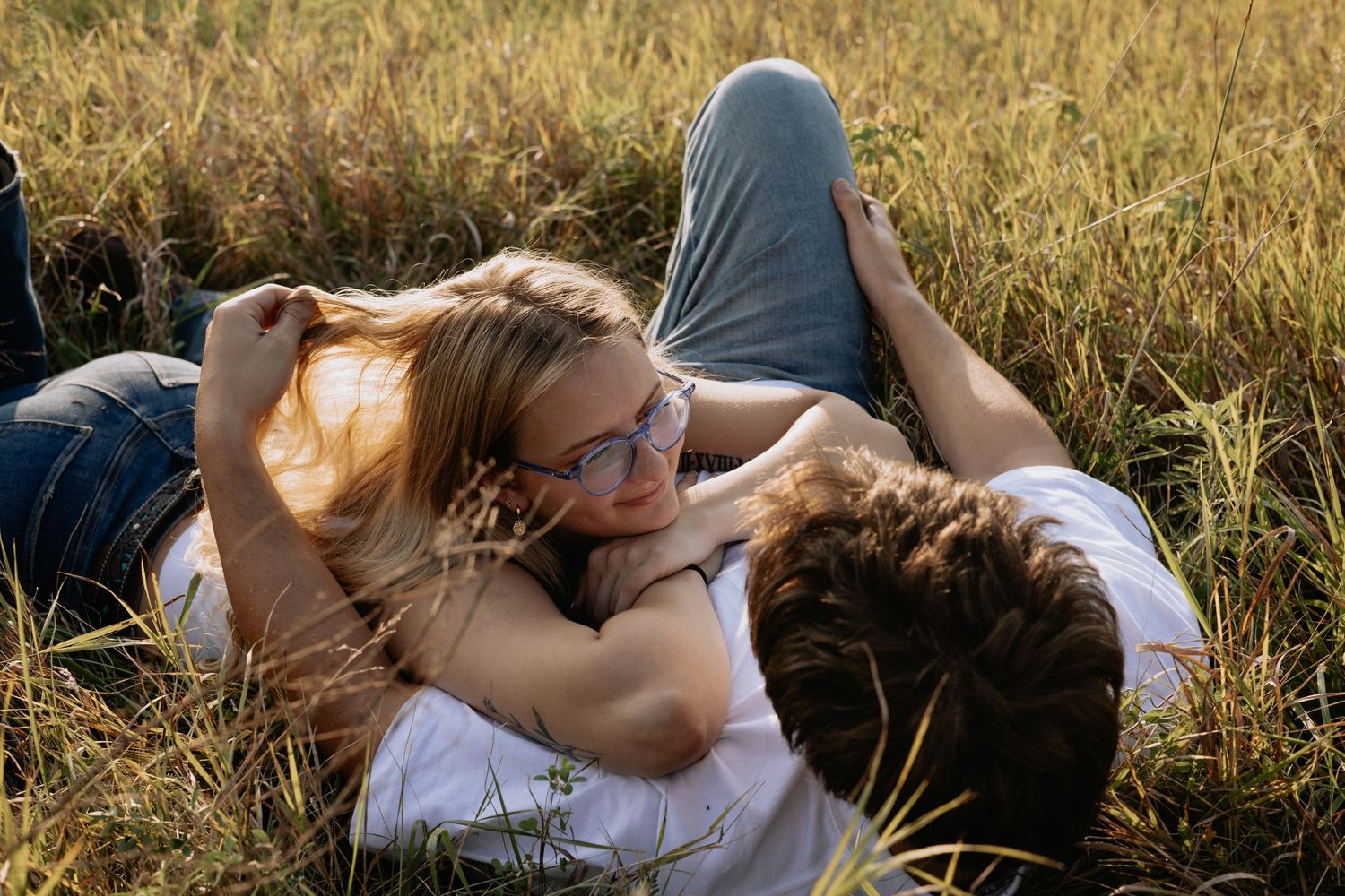 A couple lying in golden grass during sunset.