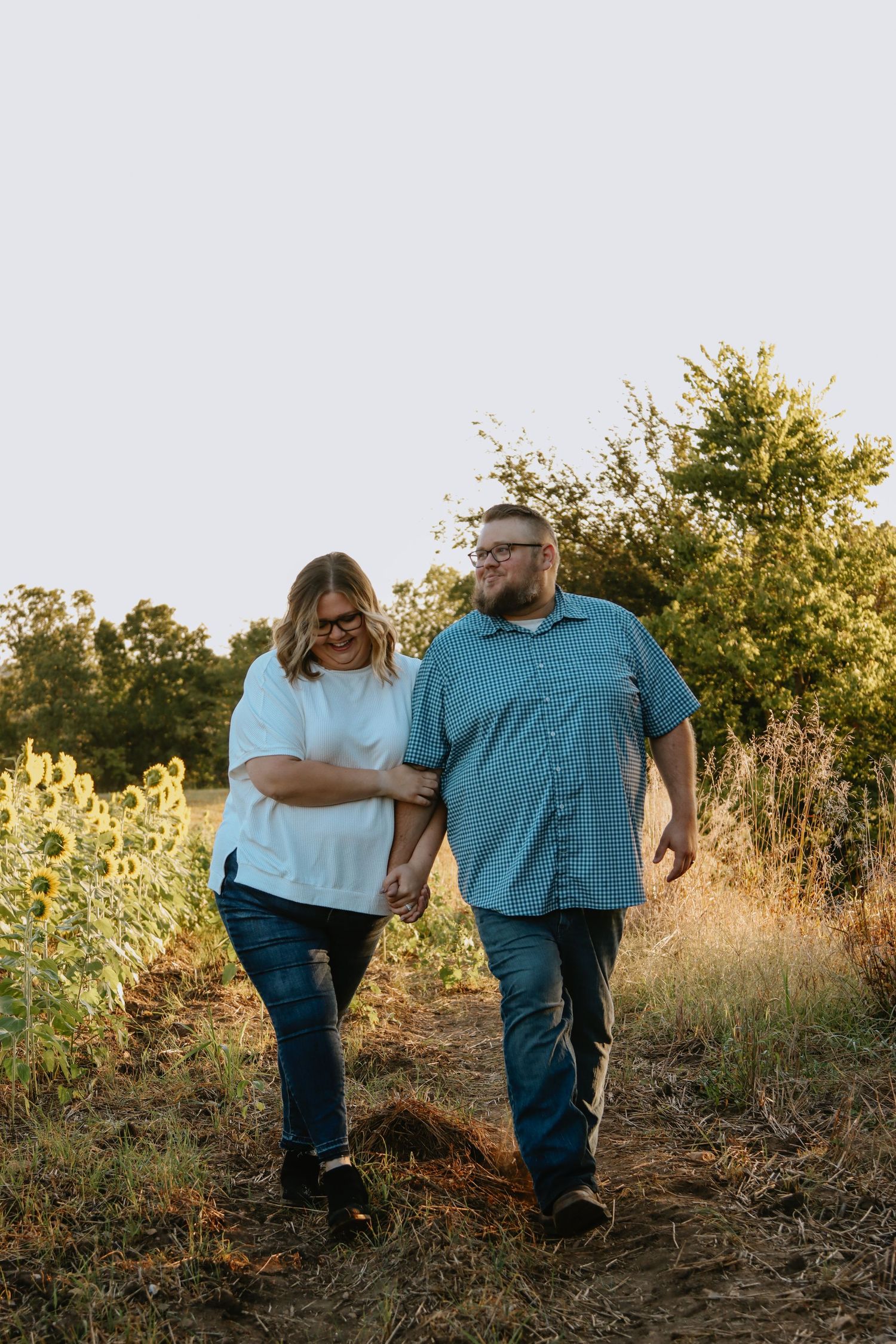 A couple walking together holding hands in golden light.