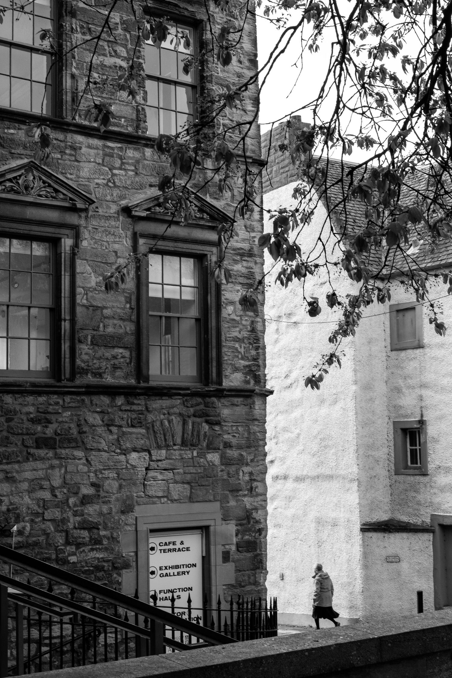 A black and white cityscape showing an old stone building next to a paler stone building.