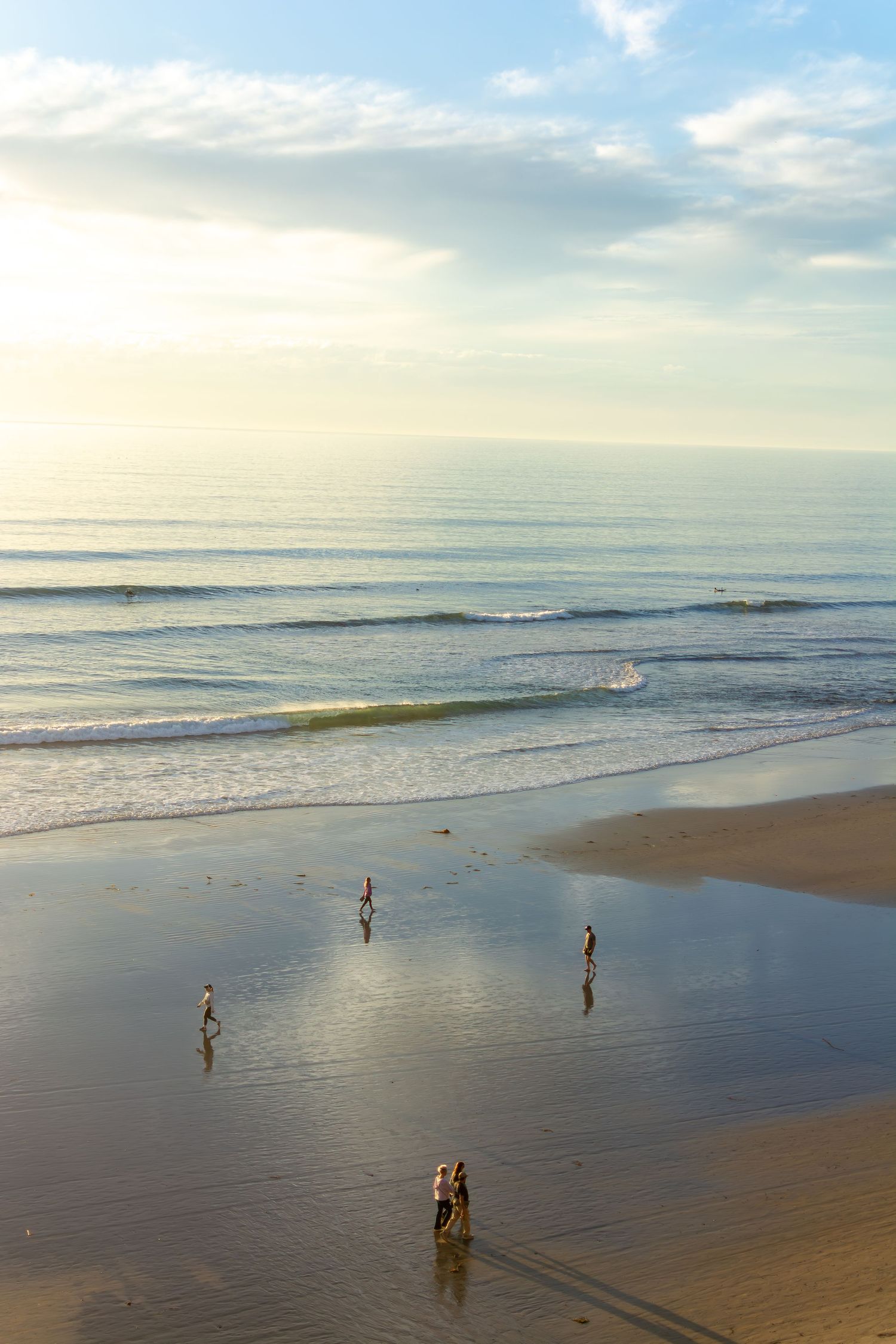 Fine art coastal print of Scripps Beach in La Jolla at golden hour with people walking on the reflective shoreline
