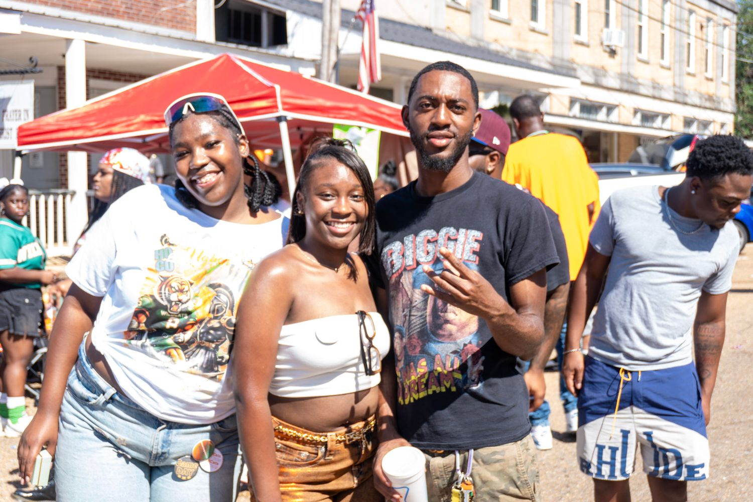 A large group of people gathered outdoors wearing Miami Dolphins team colors and casual attire at a social event.