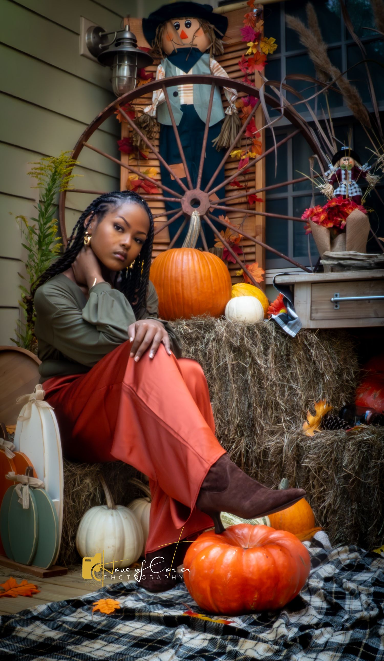 Autumn scene with hay bales, pumpkins, and plaid blanket on a porch.