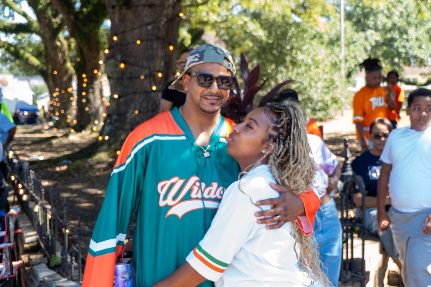 Outdoor party scene with Miami Dolphins fans wearing team merchandise and socializing.