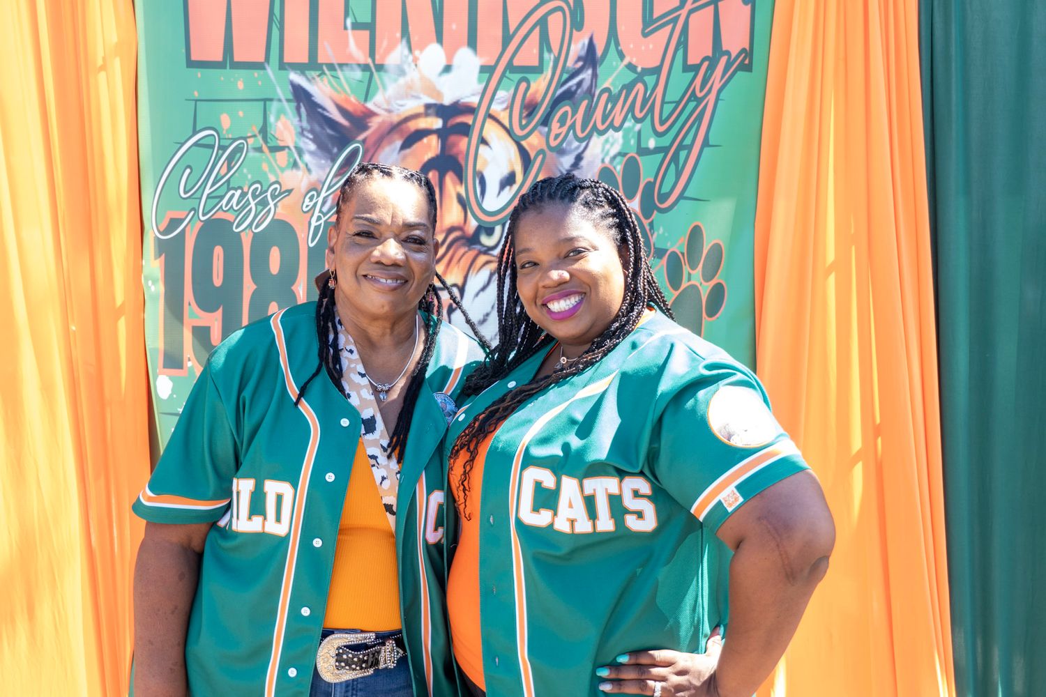 Decorative backdrop in teal and orange with sports team branding at a social event.