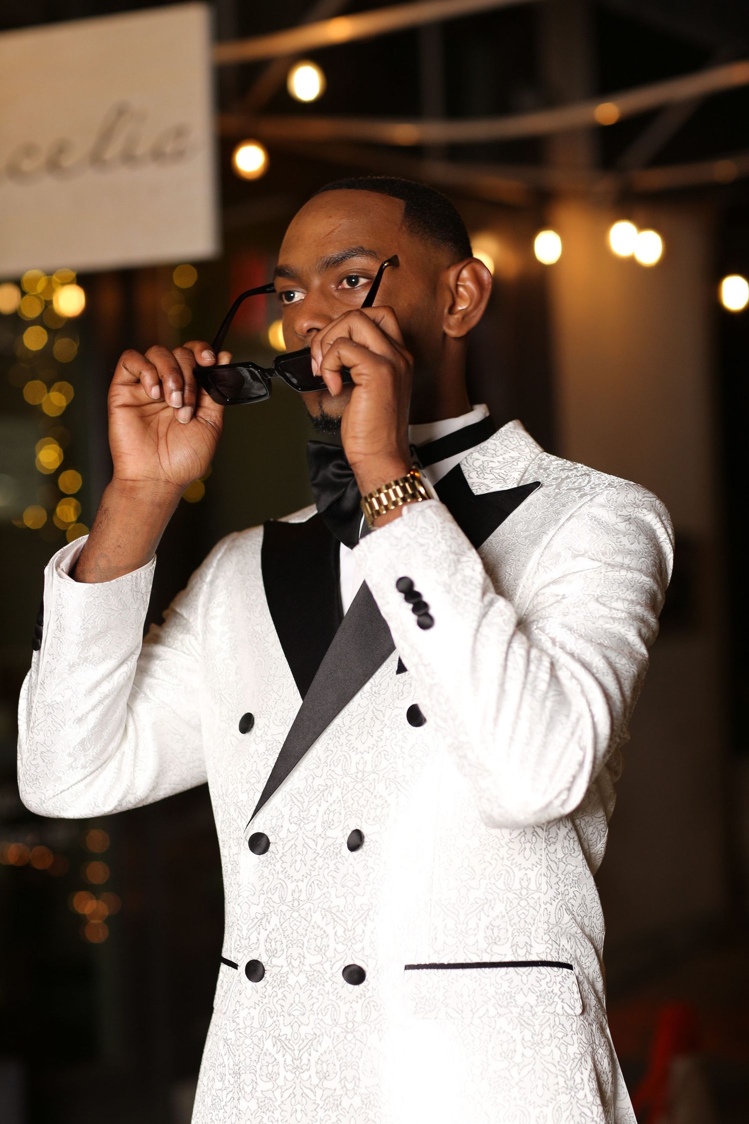 A person in a white tuxedo jacket adjusts their bowtie in a series of sequential photos.