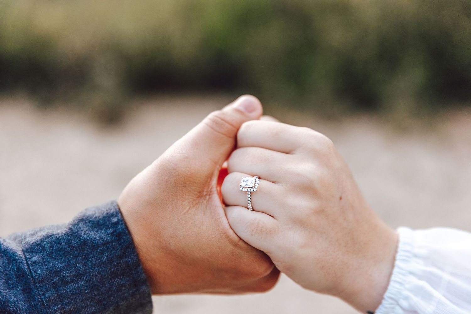 Close-up view of hands exchanging rings during an intimate wedding ceremony outdoors.