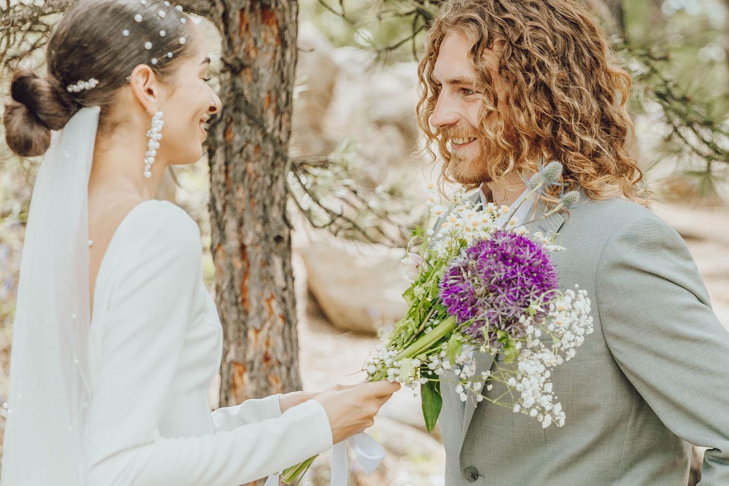 A romantic wedding photoshoot in a wooded forest setting with natural light filtering through the trees.