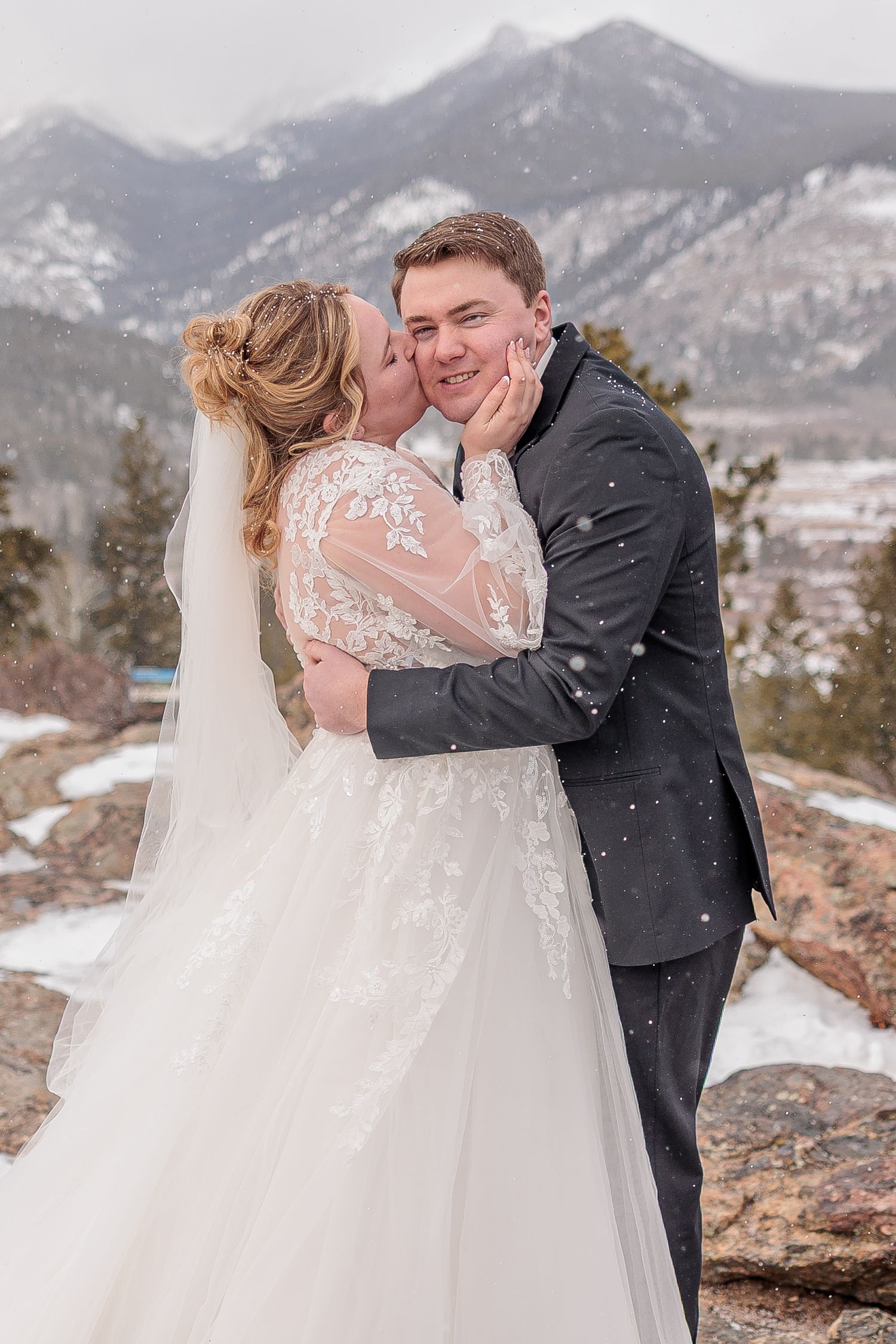 Winter wedding portraits with snowy mountain backdrop and elegant white dress details.