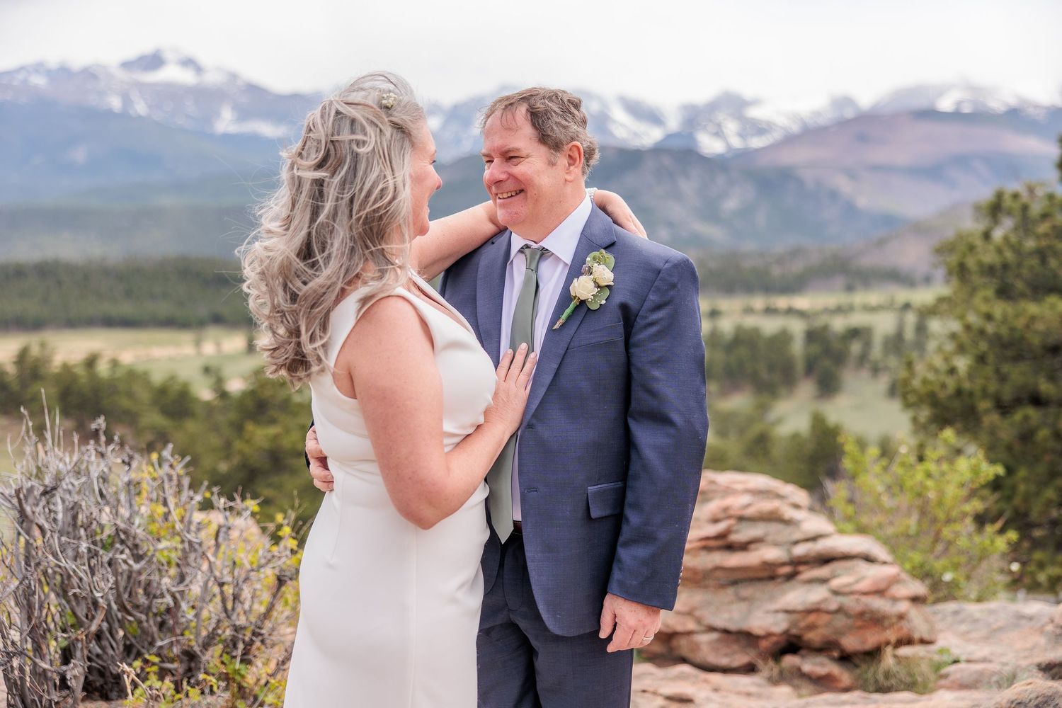 Wedding couple shares tender moment with mountain vista and rock formations in background.