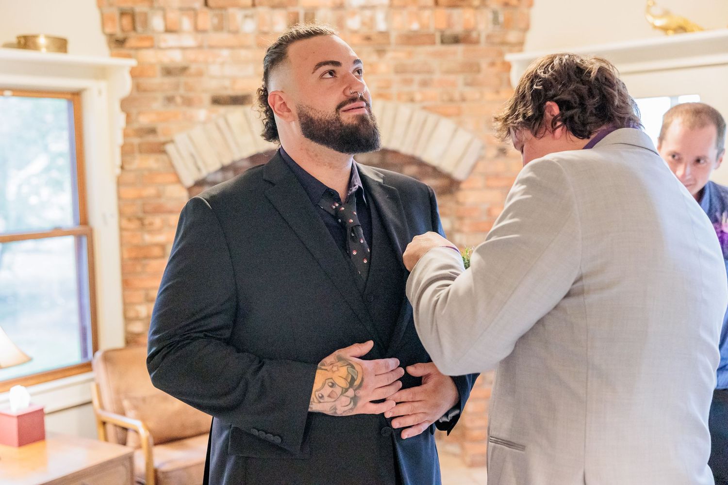 Business professionals in suits having a discussion in a modern office space with exposed brick walls.